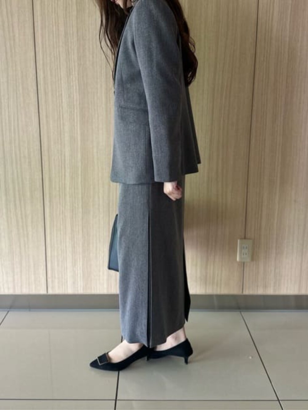 グレー系のスカート、グレー系のテーラードジャケット、ブラック系のショルダーバッグを着用したレディースの冬コーディネートの5枚目の写真