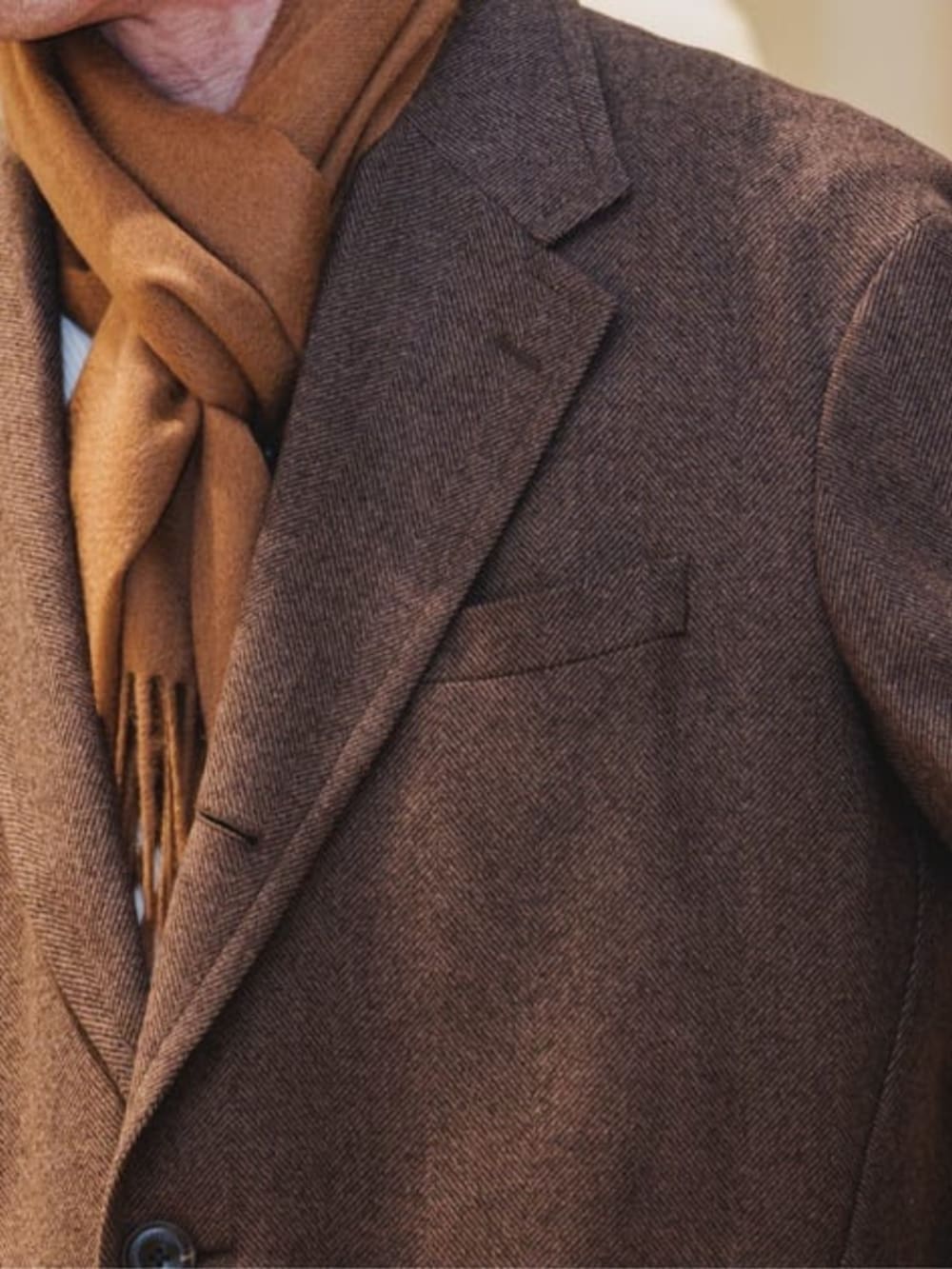 ブラウン系のチェスターコートを着用したメンズの冬コーディネートの2枚目の写真