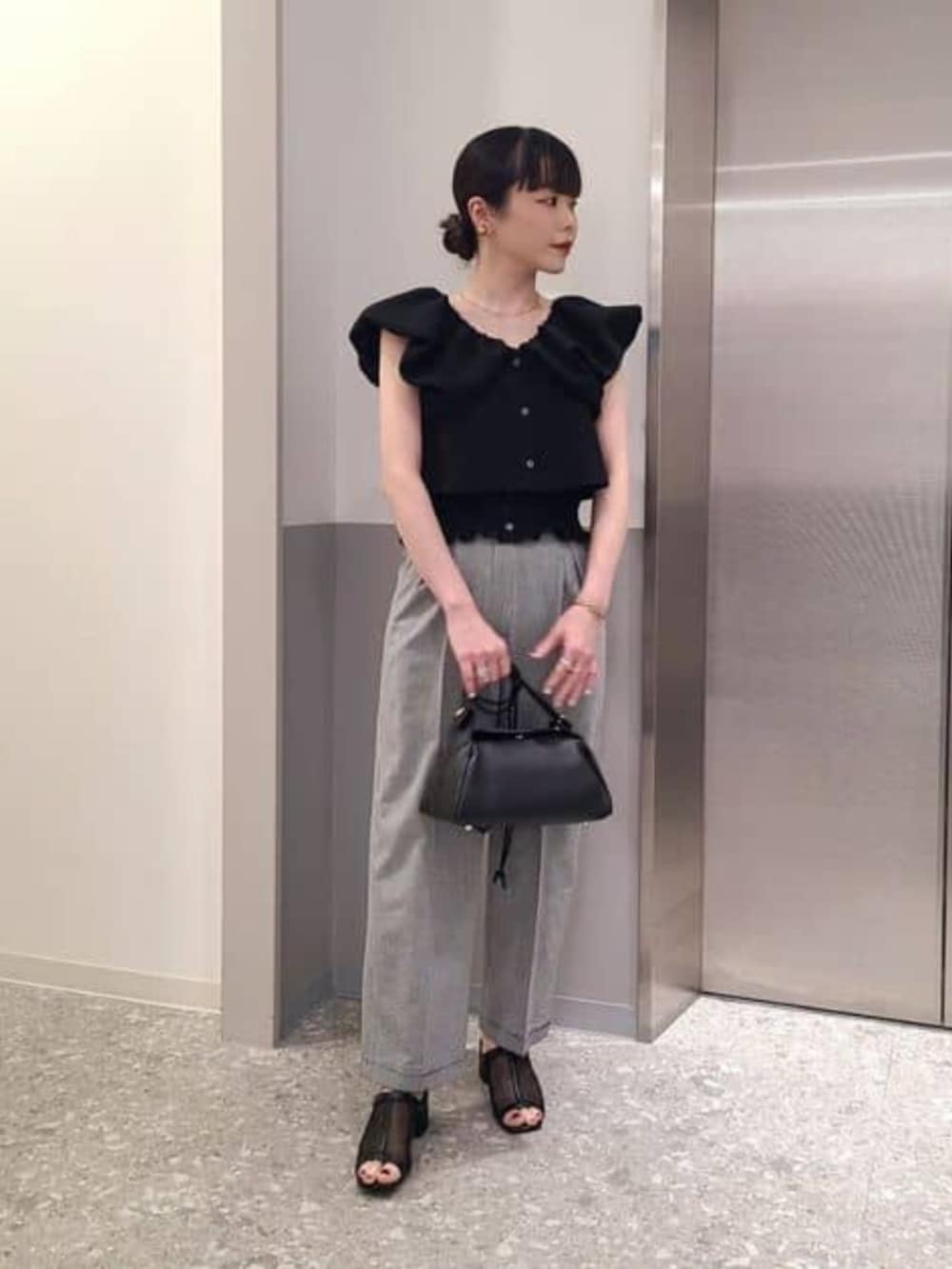 ブラック系のシャツ/ブラウス、ブラック系のスラックスを着用したレディースの春コーディネートの2枚目の写真