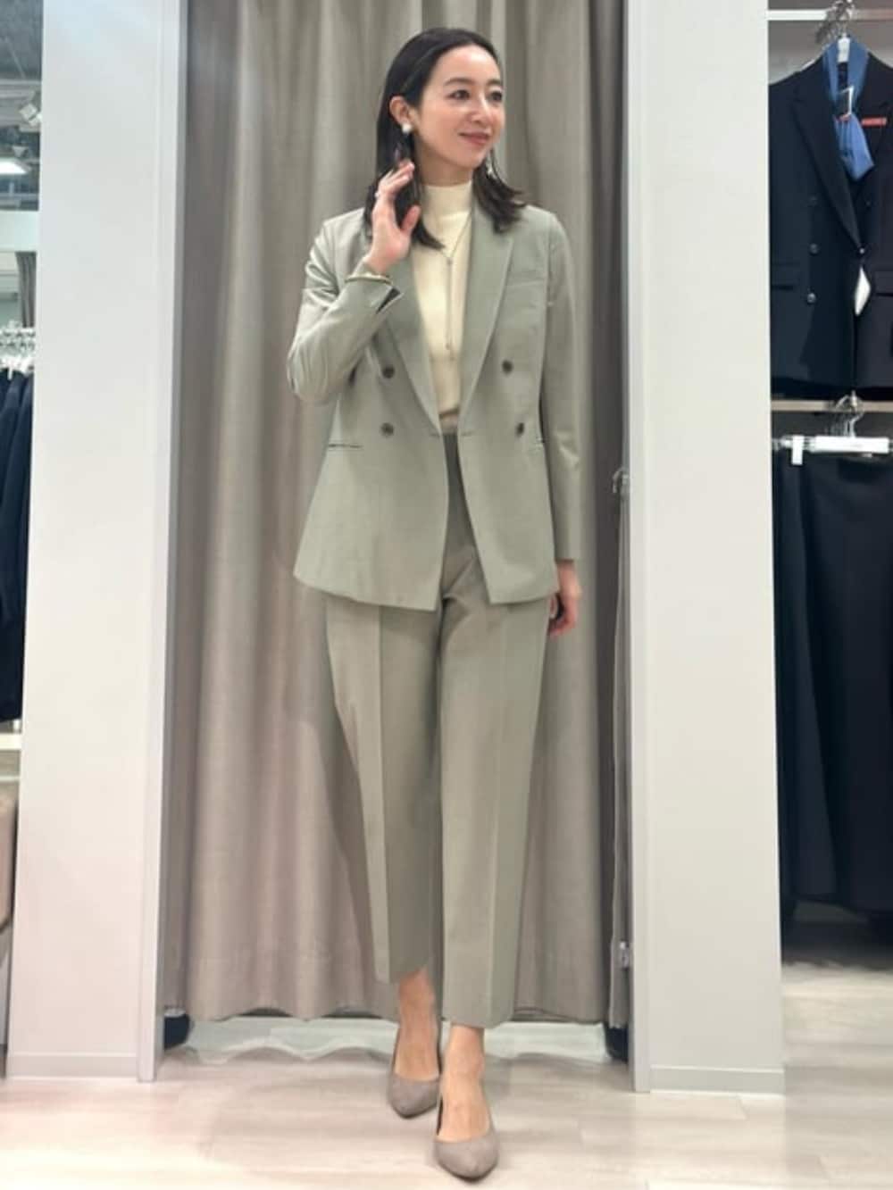 ベージュ系のニット/セーター、グリーン系のテーラードジャケット、グリーン系のスラックスを着用したレディースの冬コーディネートの5枚目の写真