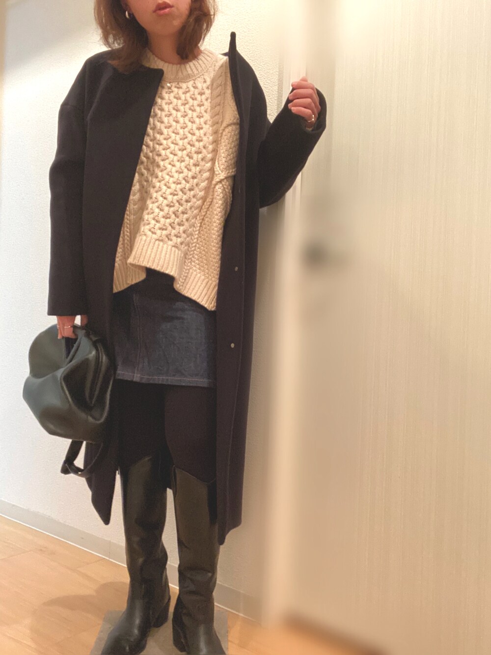 ホワイト系のニット/セーター、ブルー系のデニムスカート、ブラック系のブーツを着用したレディースの冬コーディネートの2枚目の写真