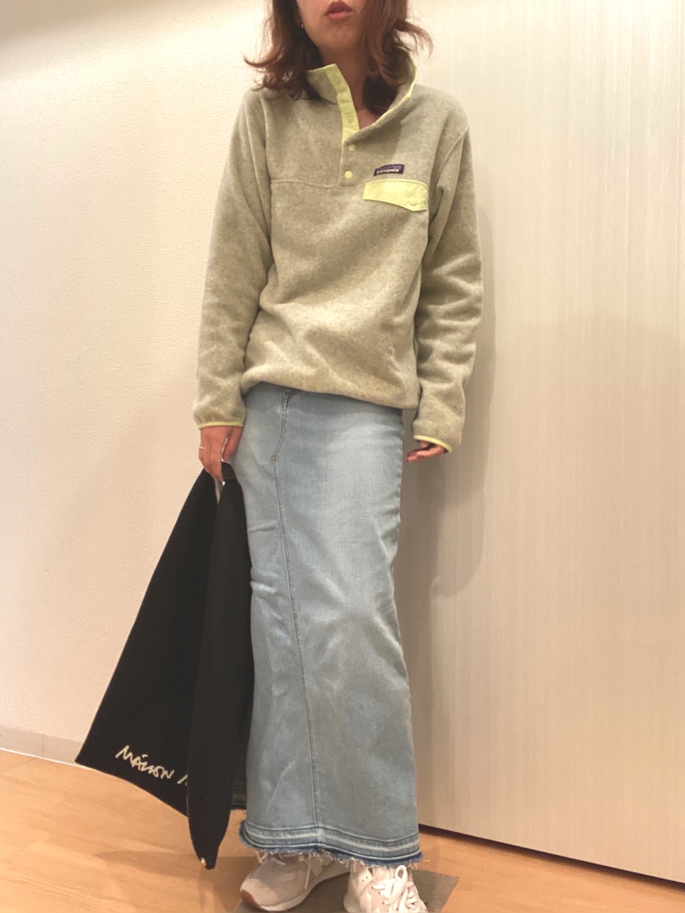 イエロー系のトップス、ブルー系のデニムスカート、ブラック系のハンドバッグを着用したレディースの秋コーディネートの3枚目の写真