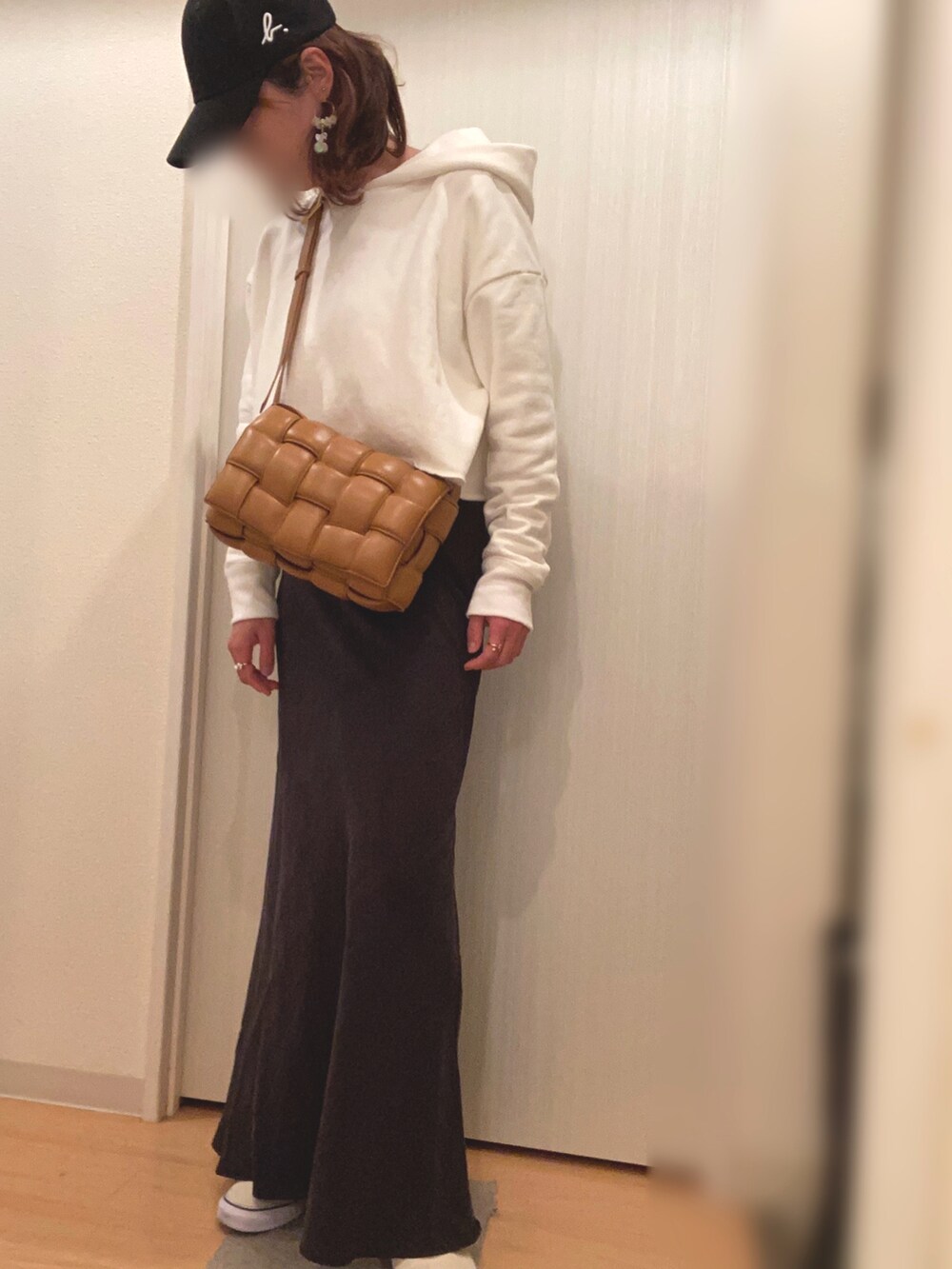 ホワイト系のパーカー、ブラック系のスカート、ホワイト系のスニーカーを着用したレディースの春コーディネートの2枚目の写真