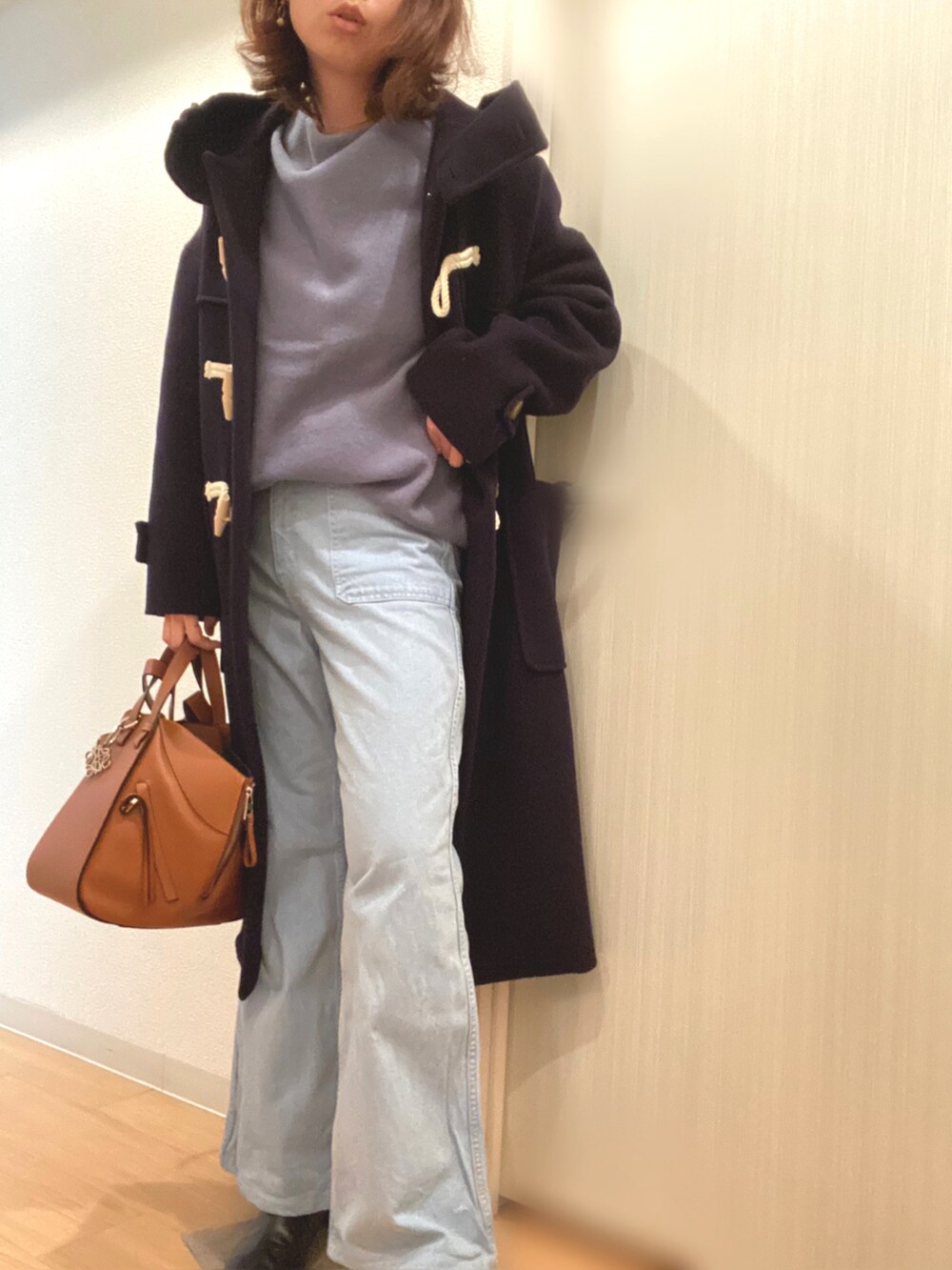 ブルー系のニット/セーター、ブルー系のデニムパンツ、ブラウン系のハンドバッグを着用したレディースの冬コーディネートの2枚目の写真