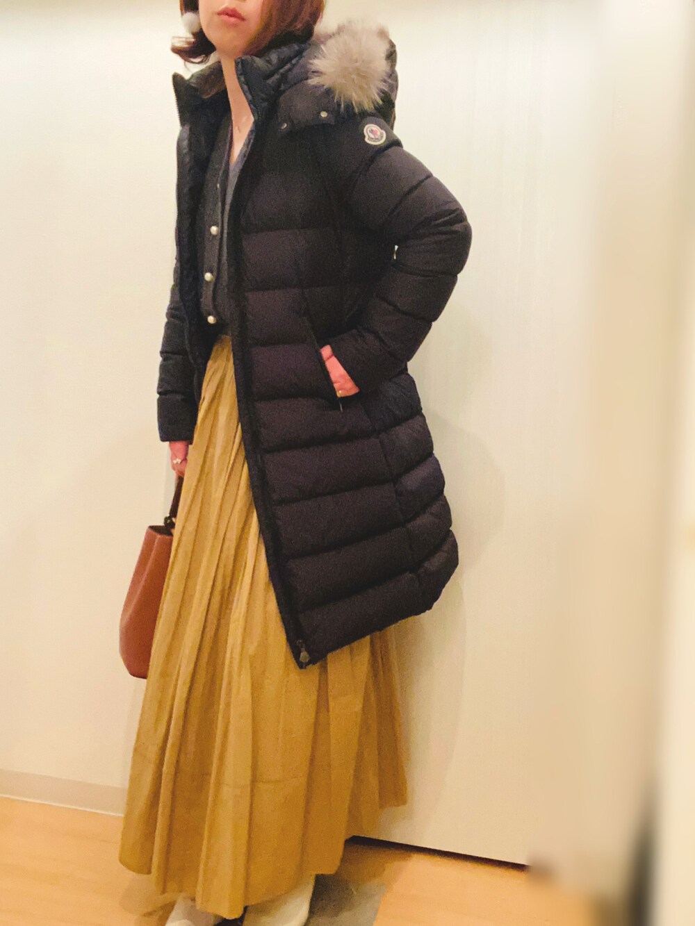 グレー系のカーディガン/ボレロ、イエロー系のスカート、ホワイト系のブーツを着用したレディースの冬コーディネートの5枚目の写真