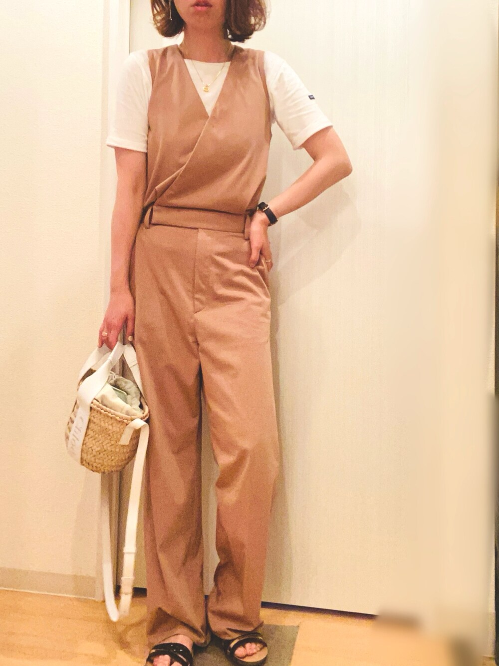 ホワイト系のかごバッグ、イエロー系のつなぎ/オールインワン、ブラック系のサンダルを着用したレディースの夏コーディネートの2枚目の写真