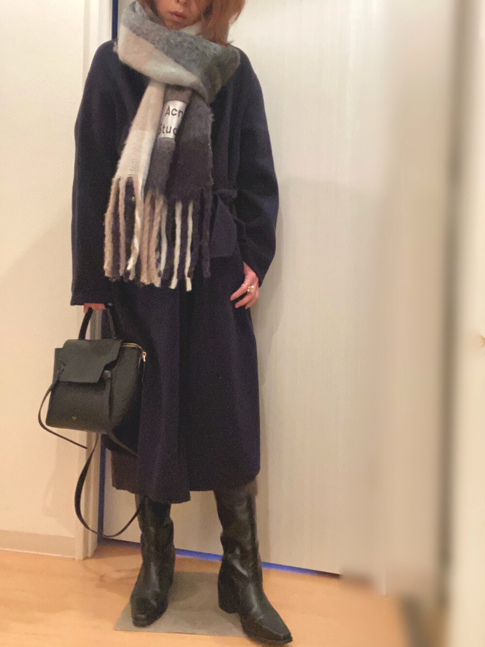 グリーン系のワンピース、ブルー系のその他アウター、ブラック系のブーツを着用したレディースの冬コーディネートの2枚目の写真