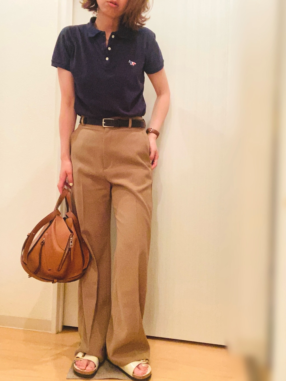 ブルー系のポロシャツ、ベージュ系のスラックス、ベージュ系のサンダルを着用したレディースの夏コーディネートの2枚目の写真