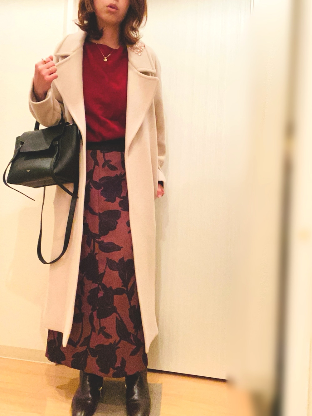 レッド系のニット/セーター、ブラウン系のスカート、ブラウン系のブーツを着用したレディースの冬コーディネートの2枚目の写真