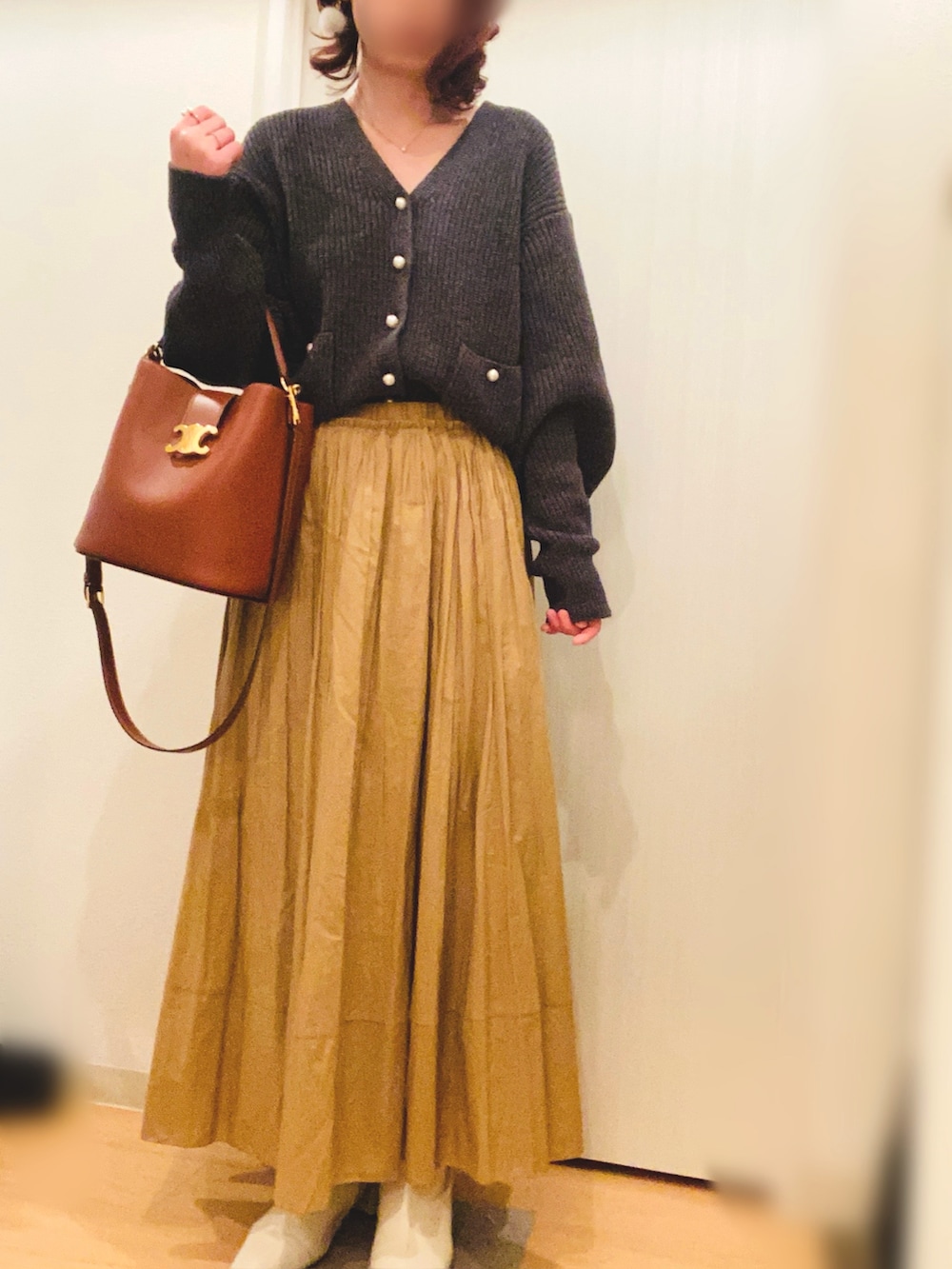 グレー系のカーディガン/ボレロ、イエロー系のスカート、ホワイト系のブーツを着用したレディースの冬コーディネートの4枚目の写真
