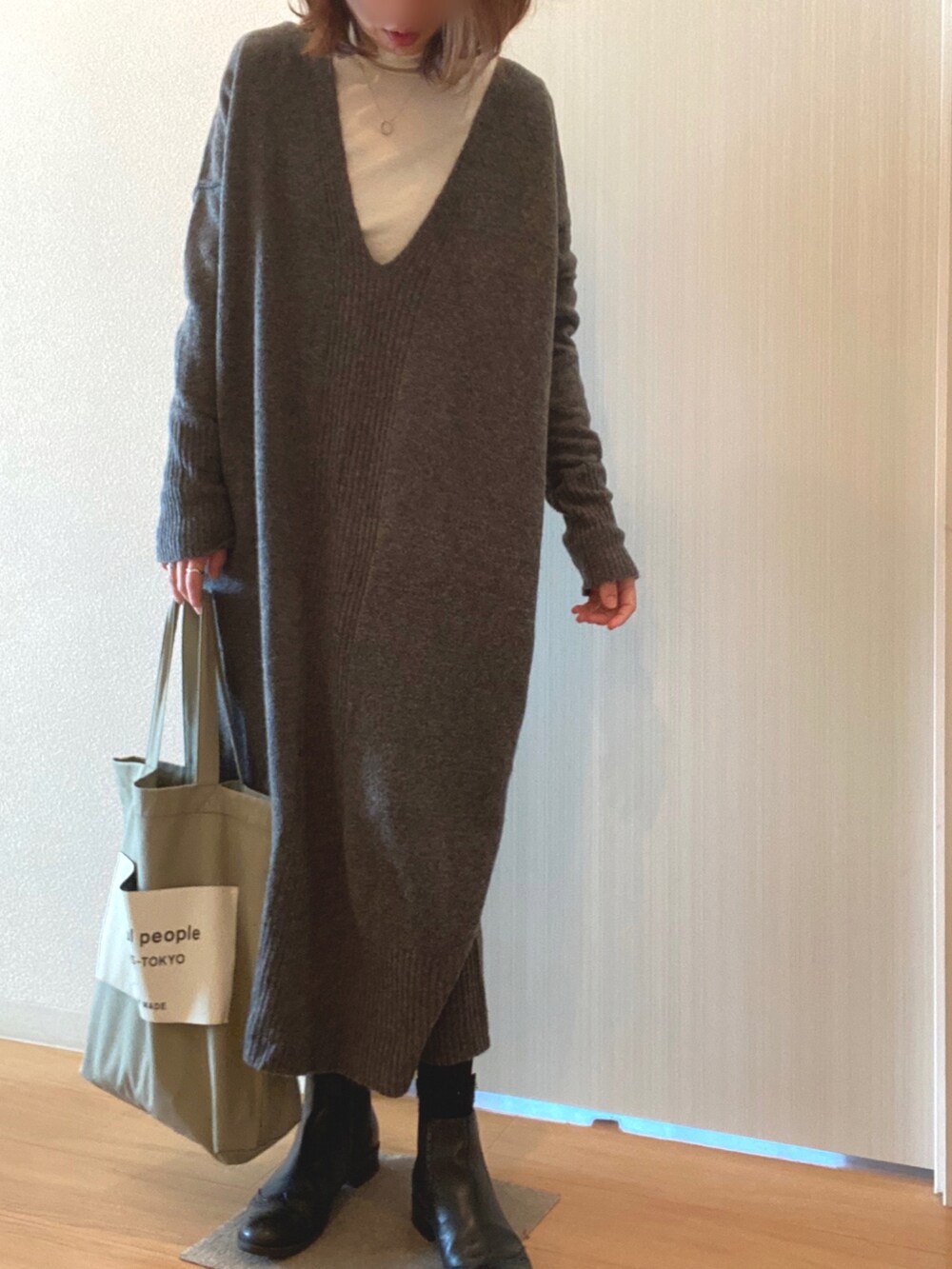 グレー系のワンピース、ブラック系のブーツ、グリーン系のトートバッグを着用したレディースの冬コーディネートの3枚目の写真