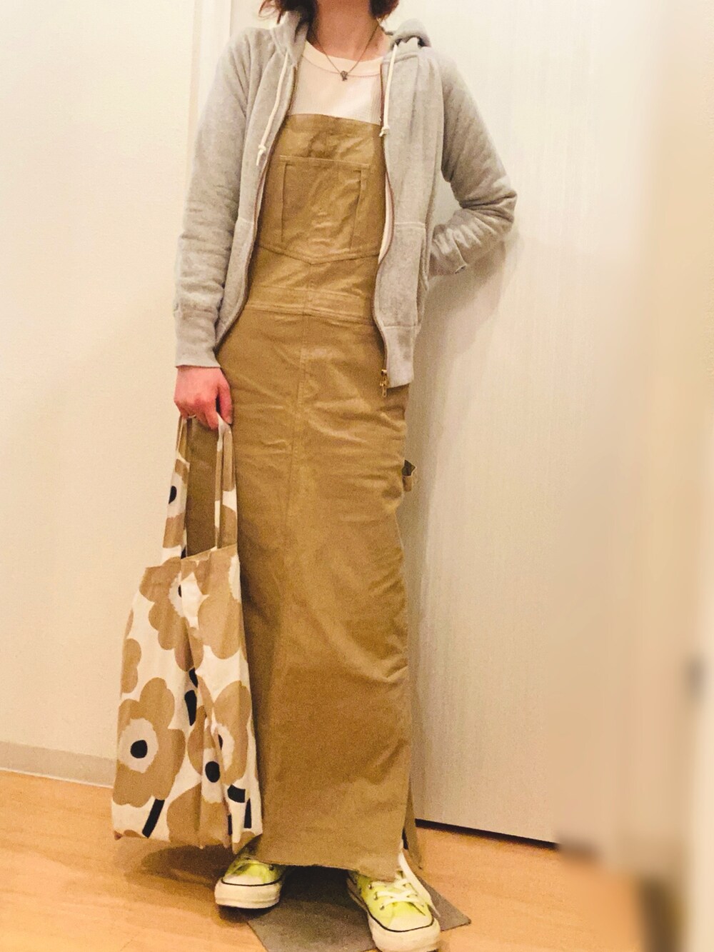 グレー系のパーカー、ベージュ系のジャンパースカート、イエロー系のスニーカーを着用したレディースの春コーディネートの3枚目の写真