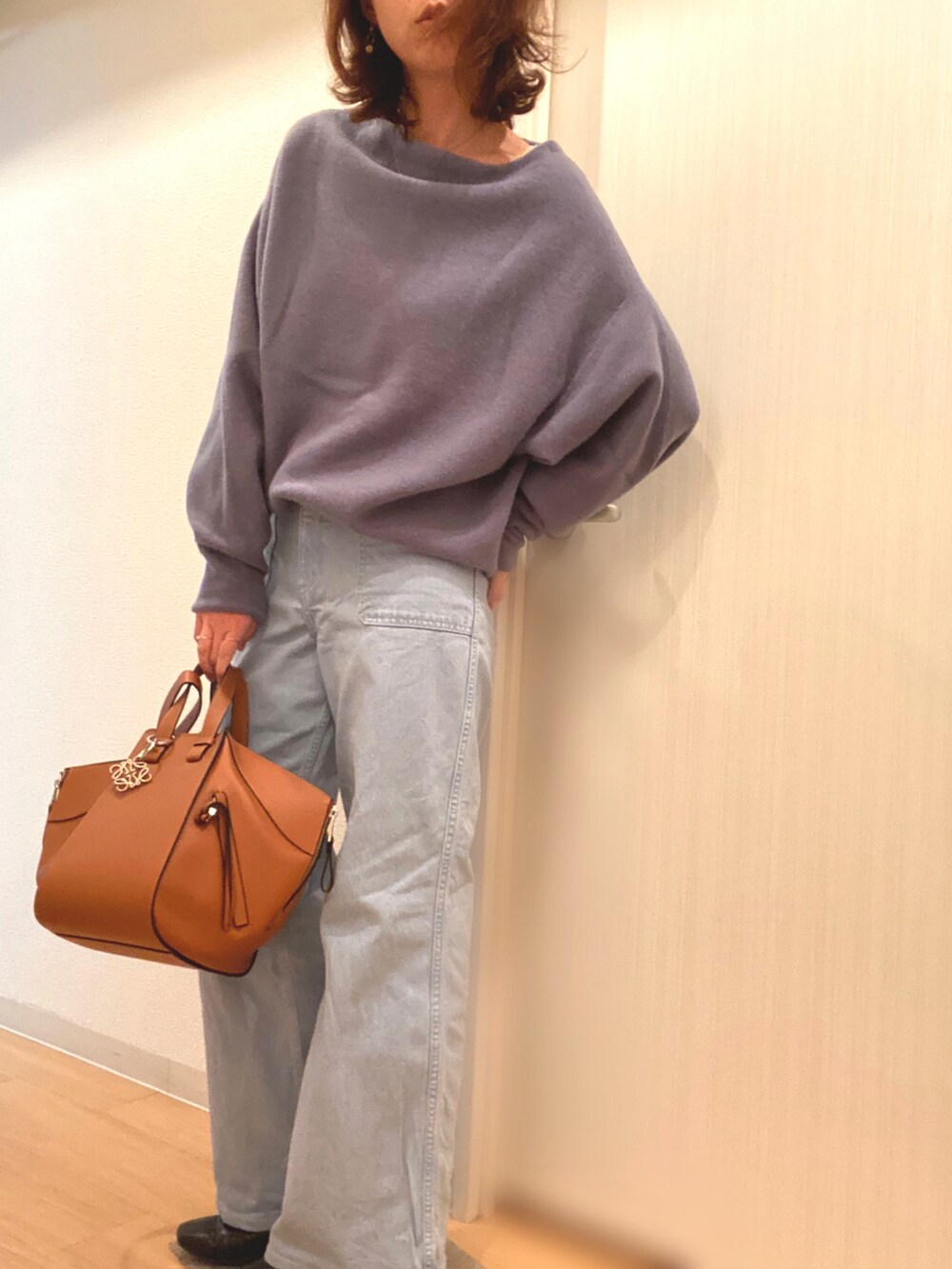 ブルー系のニット/セーター、ブルー系のデニムパンツ、ブラウン系のハンドバッグを着用したレディースの冬コーディネートの4枚目の写真