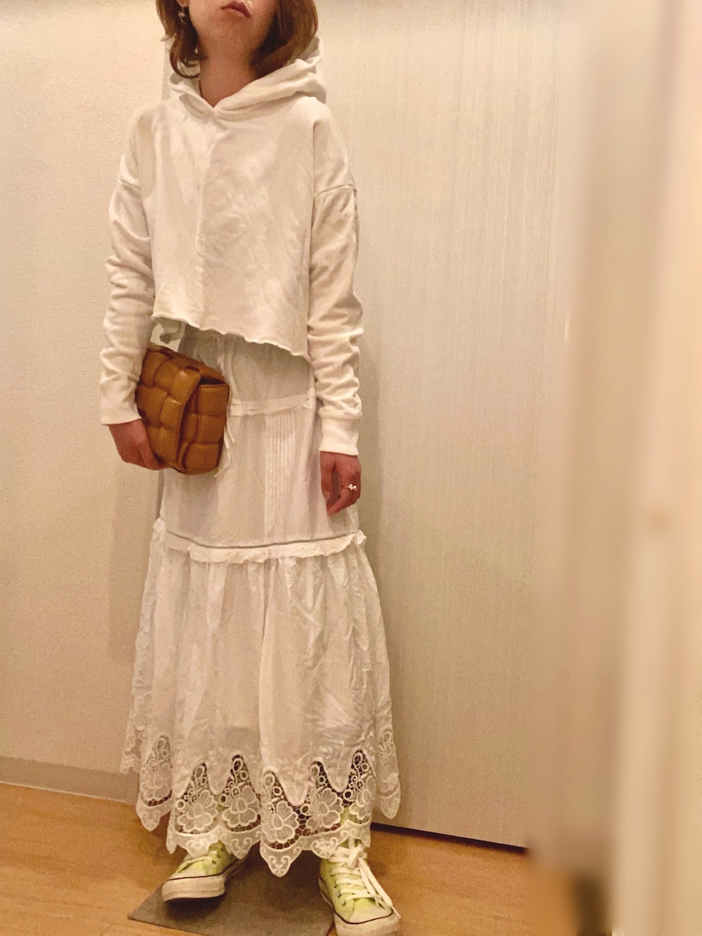 ホワイト系のパーカー、ホワイト系のスカート、イエロー系のスニーカーを着用したレディースの春コーディネートの2枚目の写真