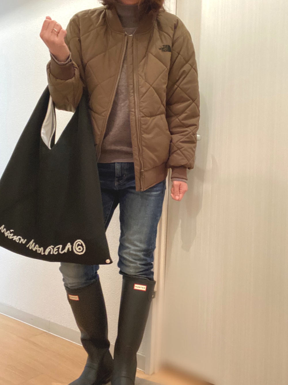 ベージュ系のニット/セーター、ブルー系のデニムパンツ、ブラック系のレインシューズを着用したレディースの冬コーディネートの2枚目の写真