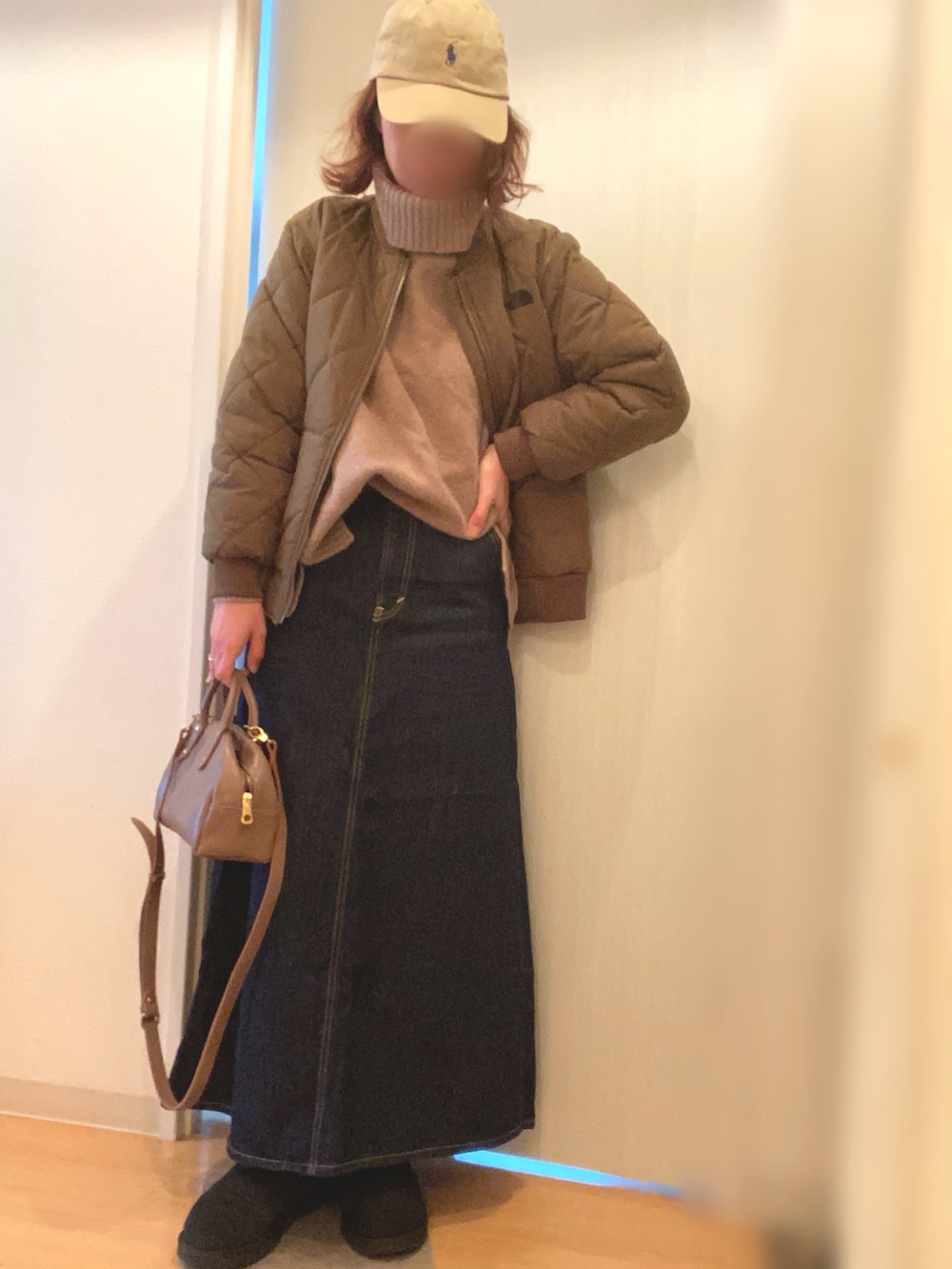 グリーン系のジャケット/アウター、ベージュ系のニット/セーター、ブルー系のデニムスカートを着用したレディースの冬コーディネートの2枚目の写真