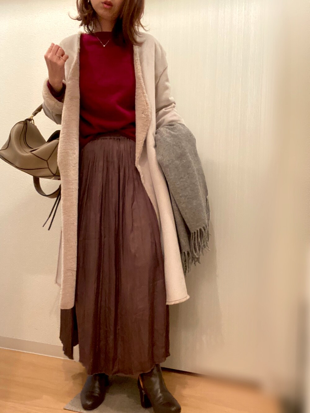 レッド系のニット/セーター、ブラウン系のスカート、ブラウン系のブーツを着用したレディースの冬コーディネートの2枚目の写真