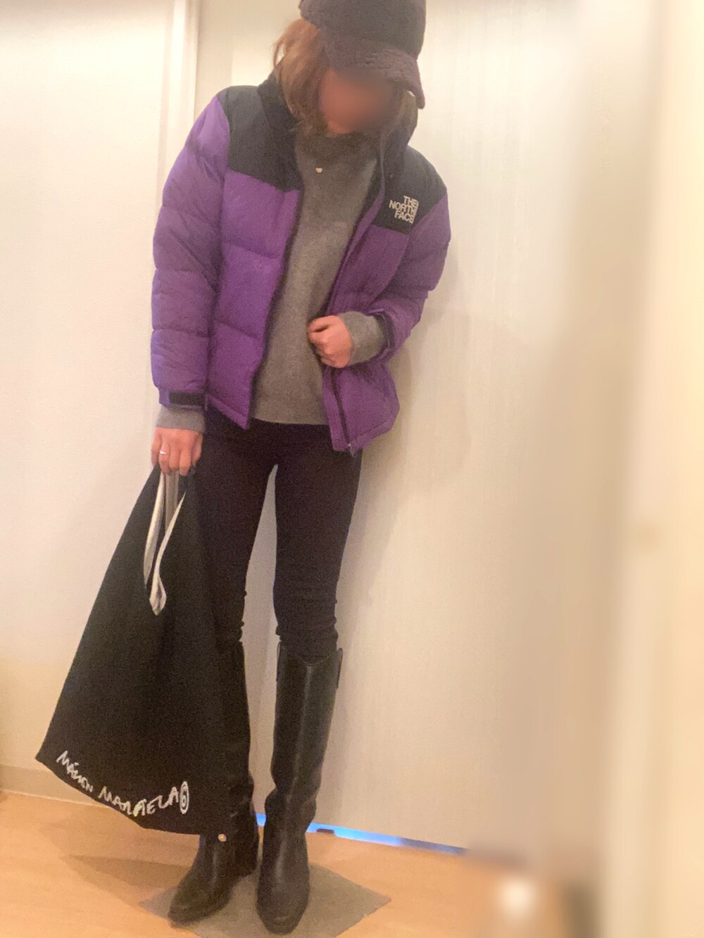 パープル系のダウンジャケット/コート、グレー系のニット/セーター、ブラック系のデニムパンツを着用したレディースの冬コーディネートの2枚目の写真