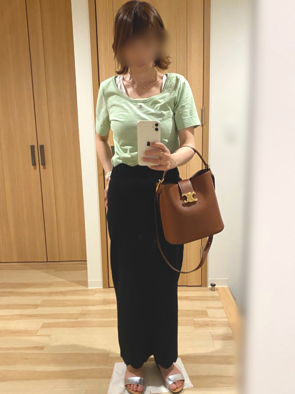 グリーン系のTシャツ/カットソー、ブラック系のスカート、シルバー系のサンダルを着用したレディースの夏コーディネートの3枚目の写真