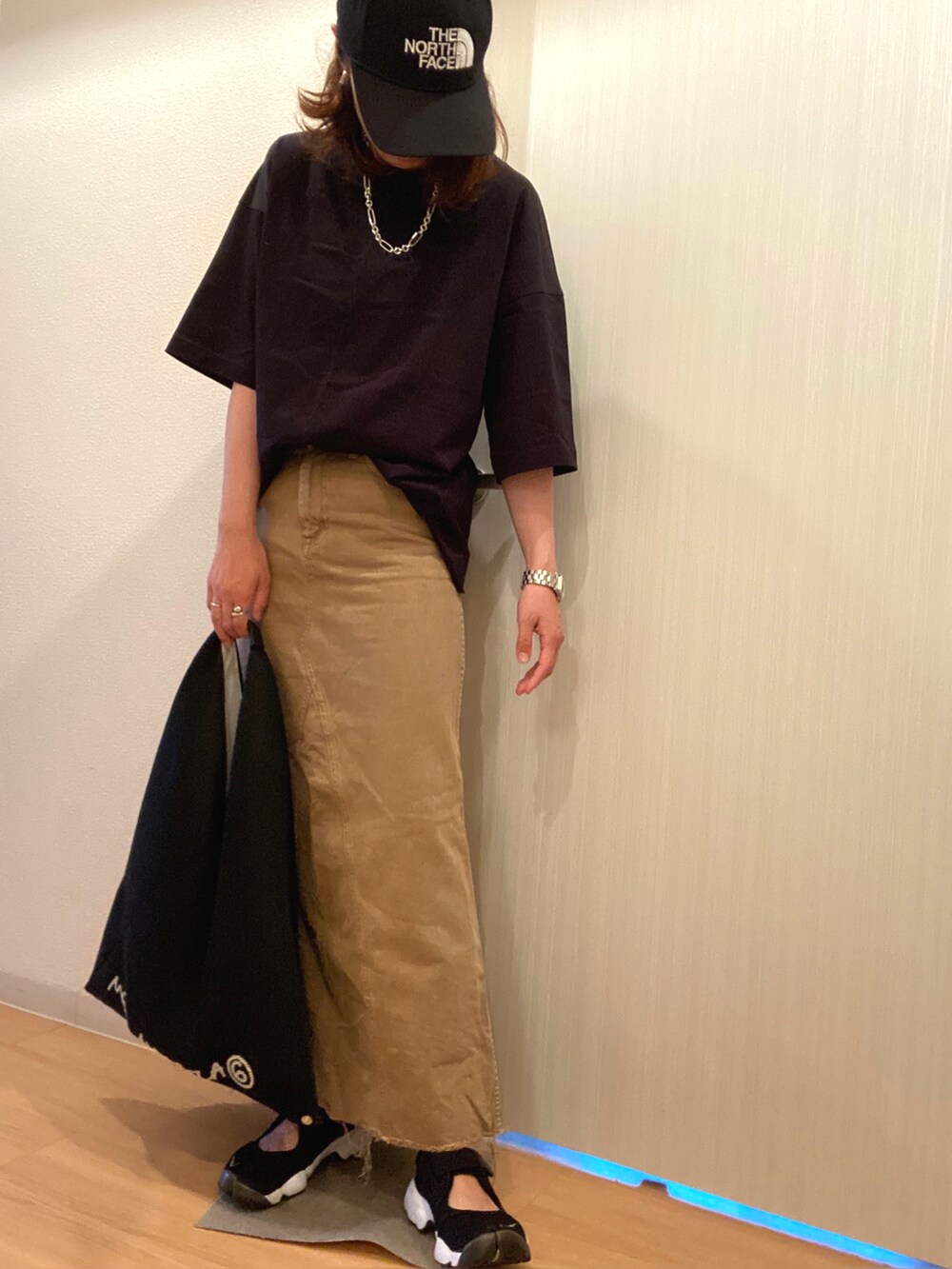 ブラック系のTシャツ/カットソー、ベージュ系のスカート、ブラック系のスニーカーを着用したレディースの夏コーディネートの2枚目の写真