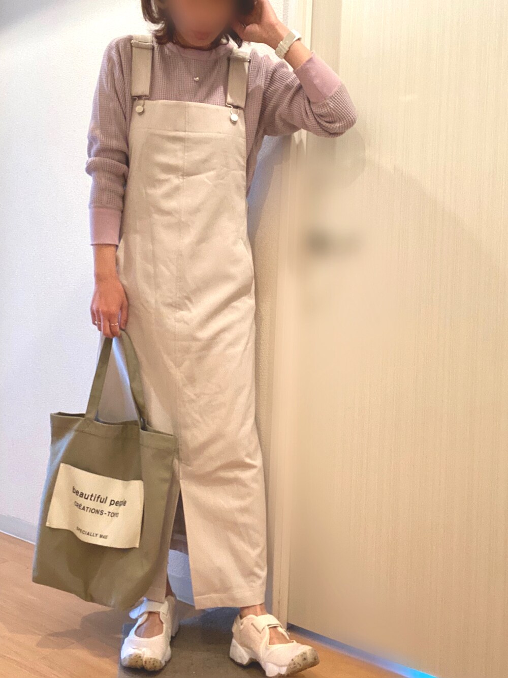 パープル系のTシャツ/カットソー、ベージュ系のジャンパースカート、ホワイト系のスニーカーを着用したレディースの春コーディネートの2枚目の写真