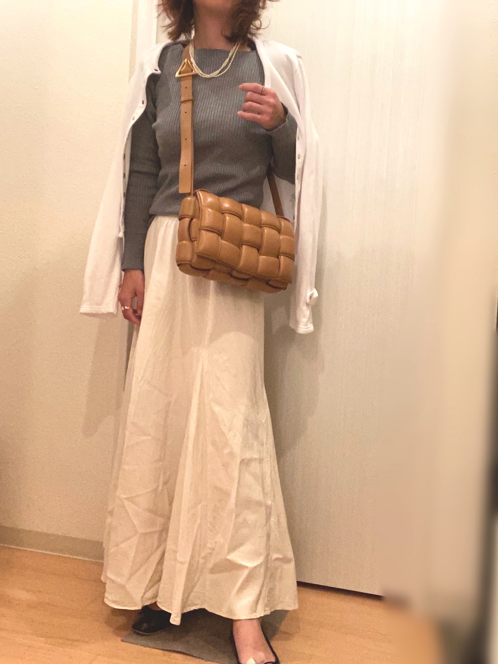グレー系のニット/セーター、ホワイト系のスカート、ホワイト系のカーディガン/ボレロを着用したレディースの秋コーディネートの2枚目の写真