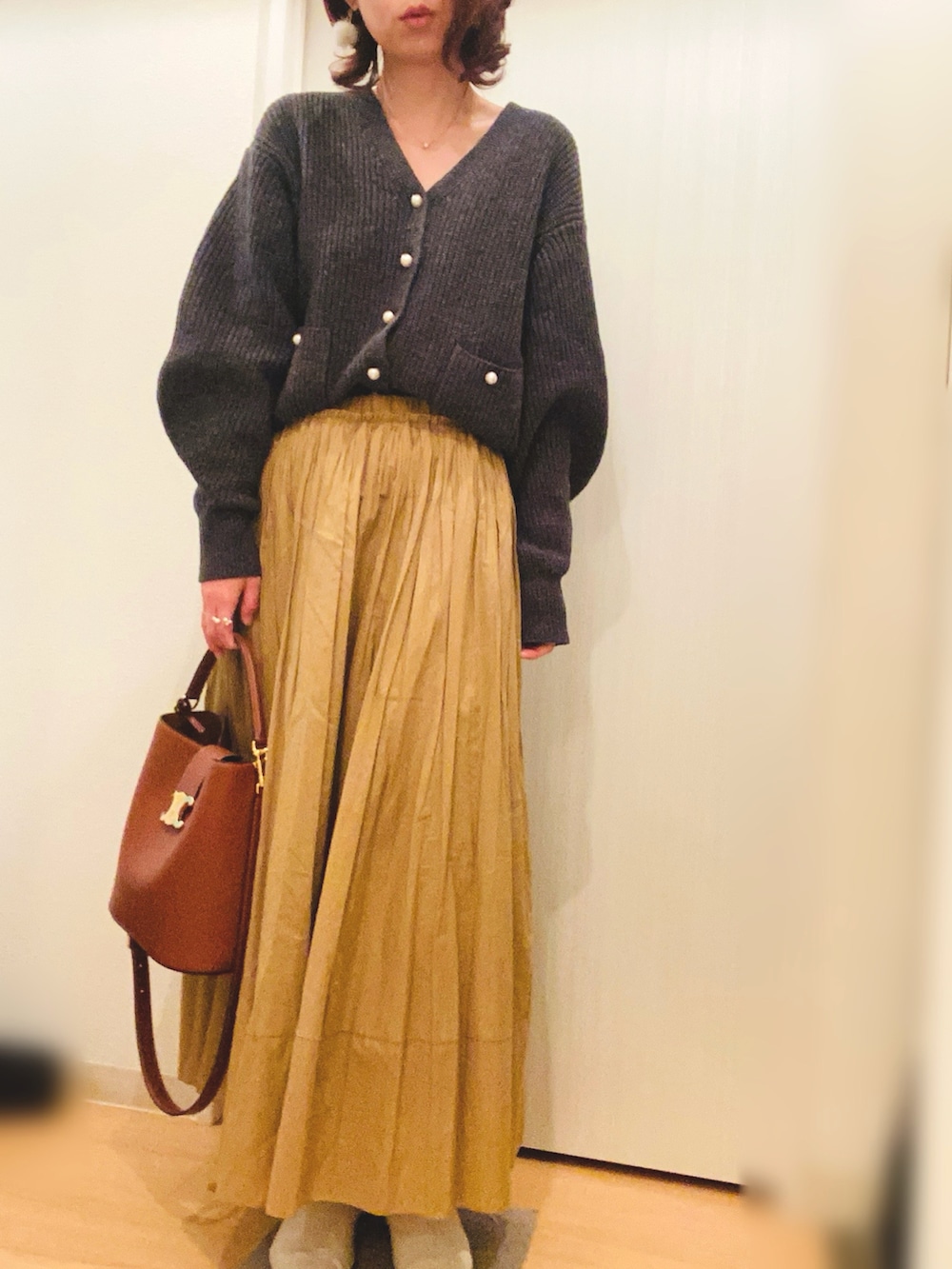グレー系のカーディガン/ボレロ、イエロー系のスカート、ホワイト系のブーツを着用したレディースの冬コーディネートの3枚目の写真