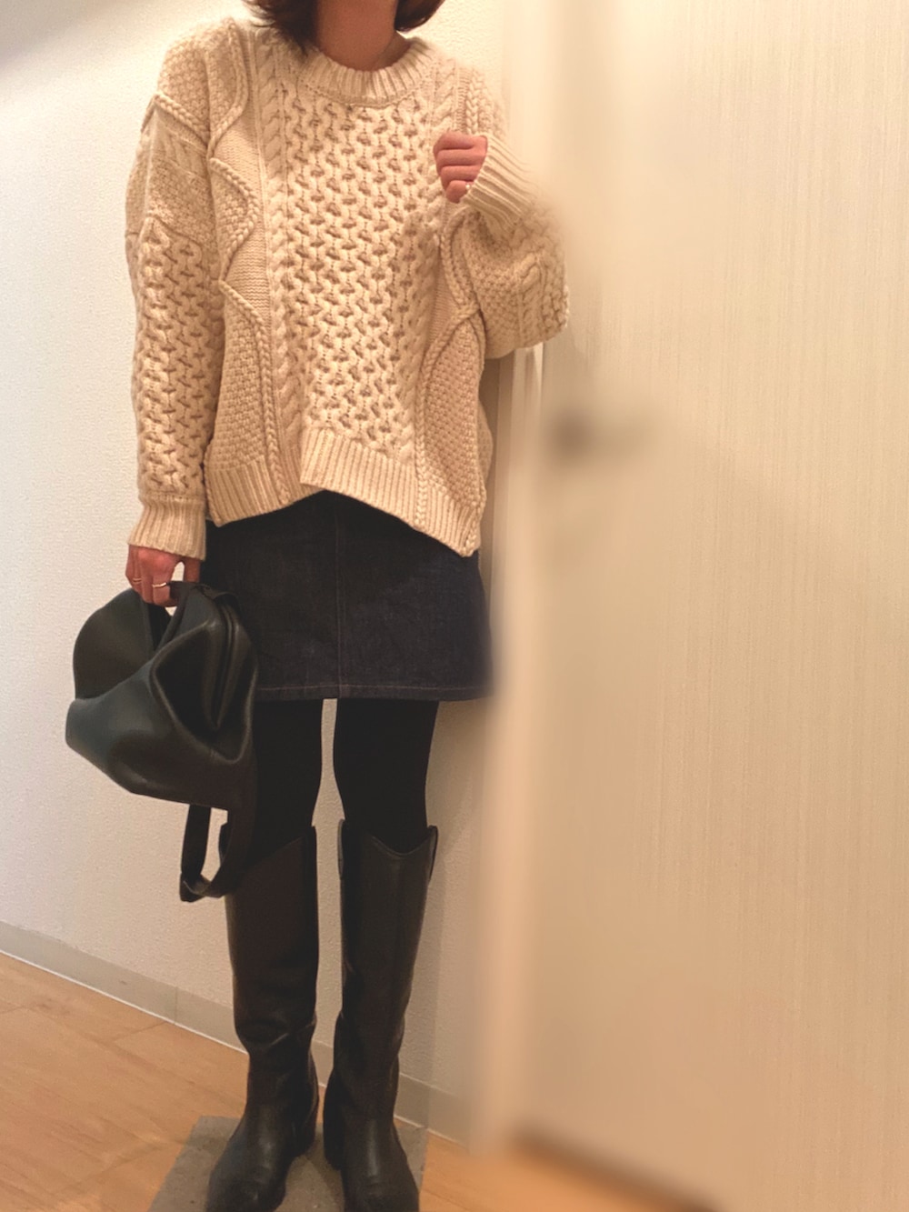 ホワイト系のニット/セーター、ブルー系のデニムスカート、ブラック系のブーツを着用したレディースの冬コーディネートの3枚目の写真