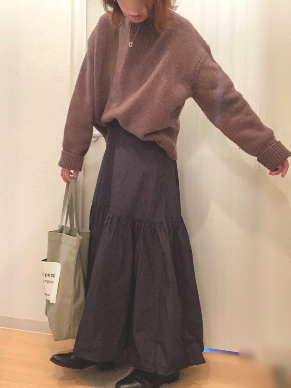 ブラウン系のニット/セーター、ブラック系のスカート、グリーン系のトートバッグを着用したレディースの冬コーディネートの3枚目の写真