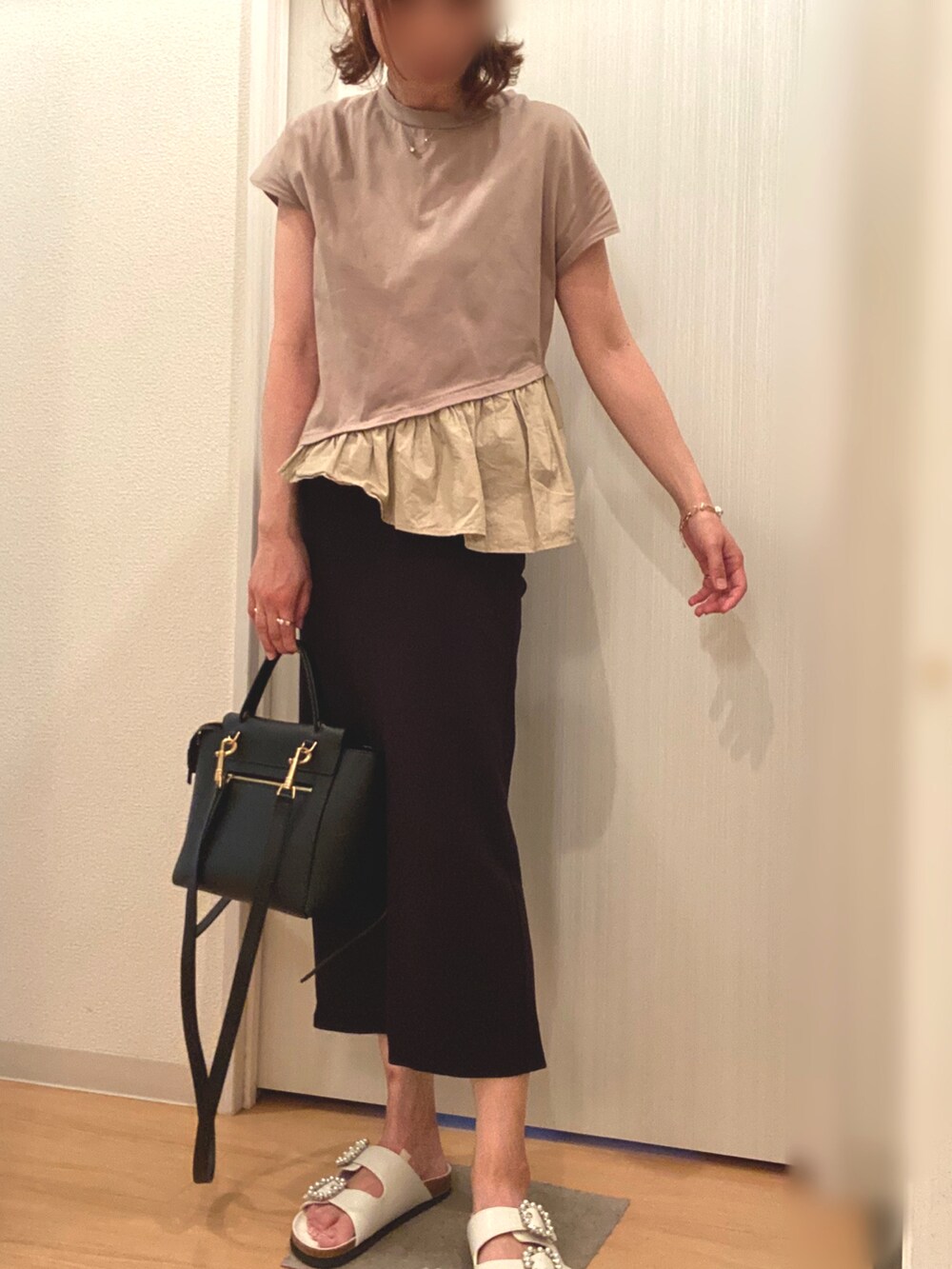 ベージュ系のTシャツ/カットソー、ブラック系のスカート、ホワイト系のサンダルを着用したレディースの夏コーディネートの2枚目の写真