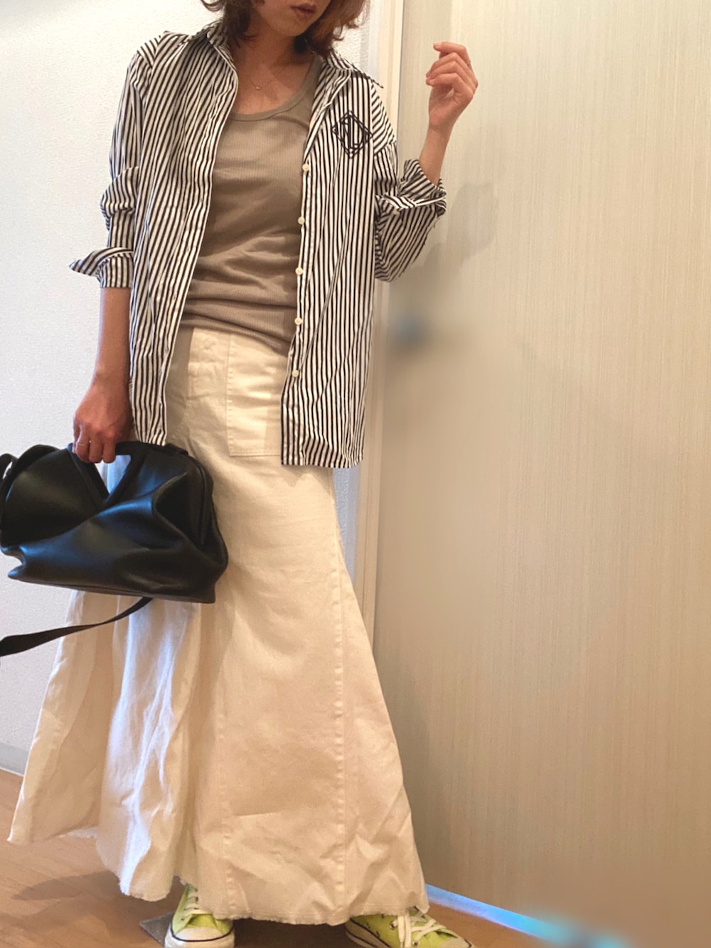 ブラック系のシャツ/ブラウス、ホワイト系のスカート、イエロー系のスニーカーを着用したレディースの春コーディネートの2枚目の写真