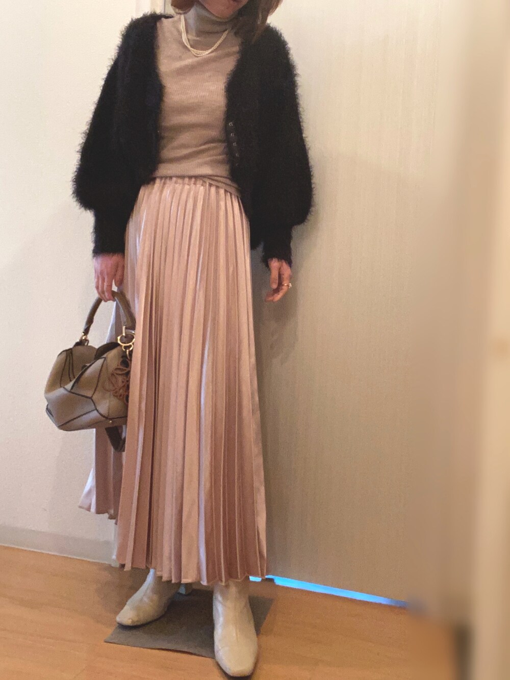 ベージュ系のスカート、ベージュ系のブーツ、ブラック系のカーディガン/ボレロを着用したレディースの春コーディネートの3枚目の写真