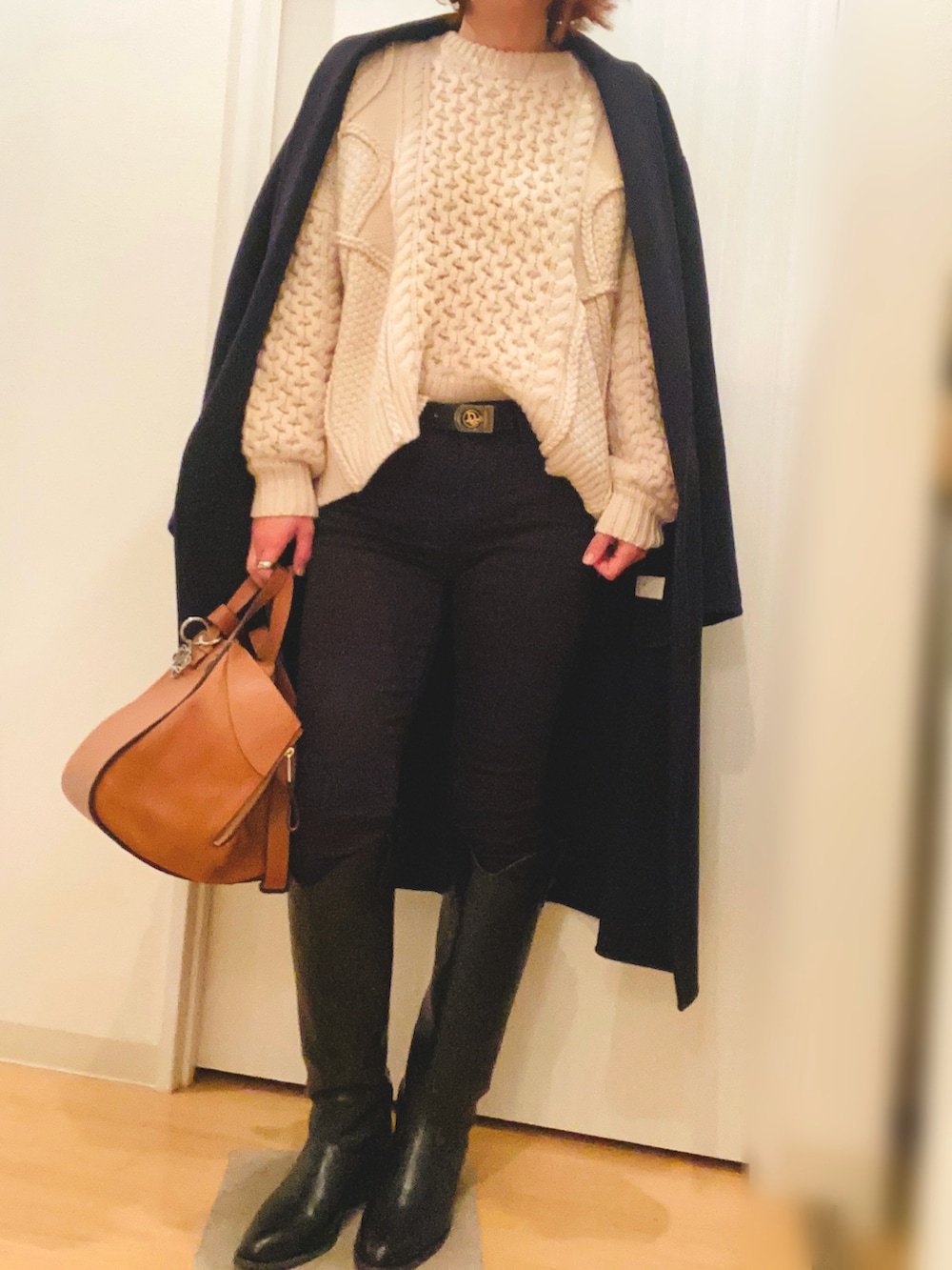 ホワイト系のニット/セーター、ブラック系のデニムパンツ、ブラック系のブーツを着用したレディースの冬コーディネートの2枚目の写真