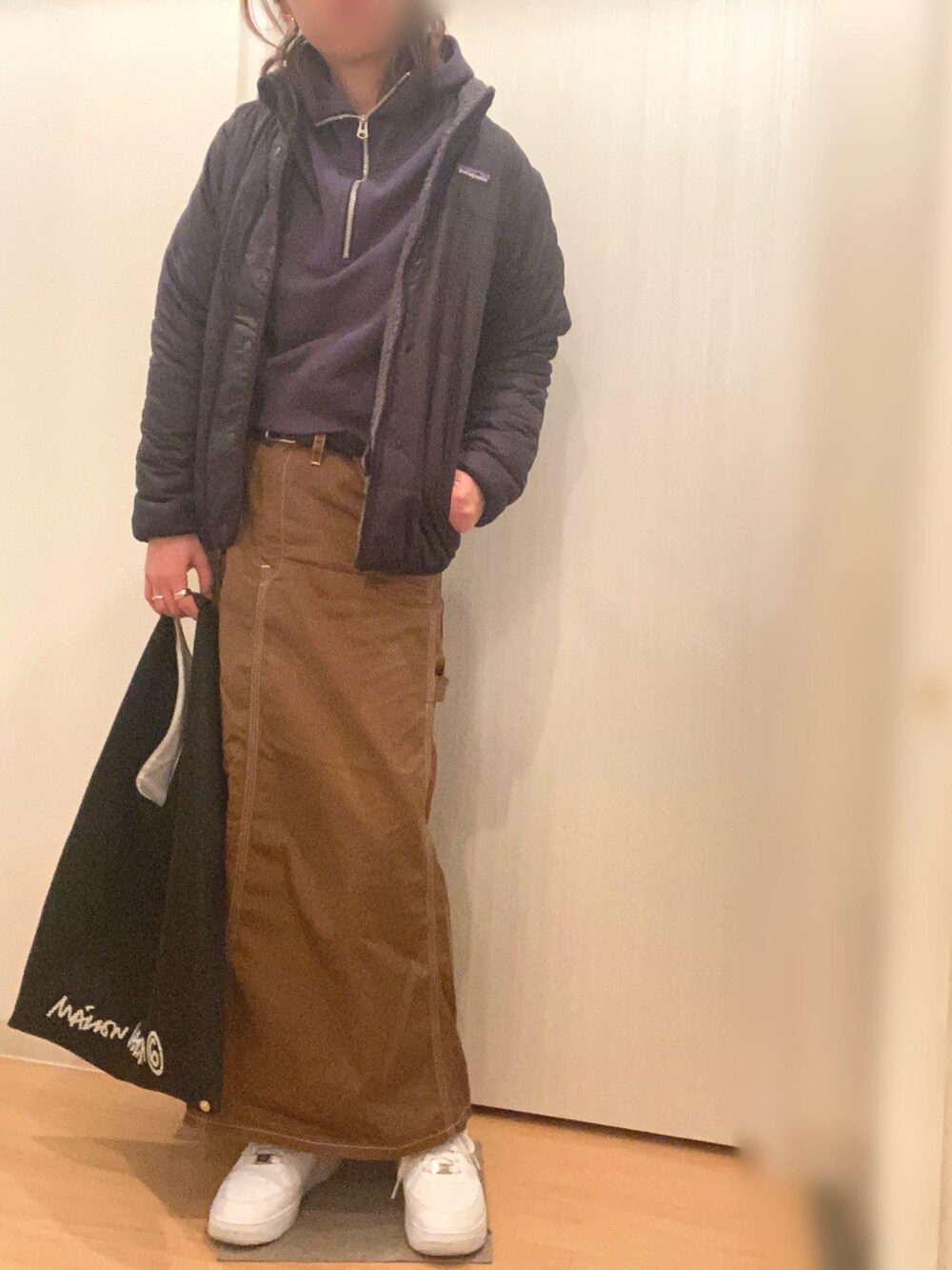 グレー系のパーカー、ブラウン系のスカート、ホワイト系のスニーカーを着用したレディースの冬コーディネートの2枚目の写真