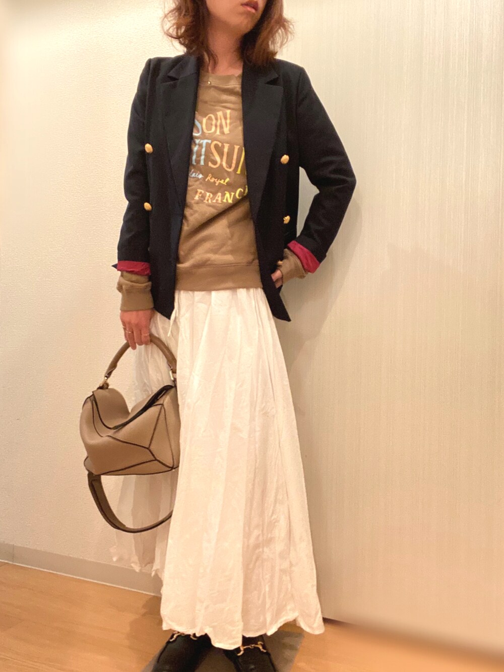 グリーン系のスウェット、ブルー系のテーラードジャケット、ホワイト系のスカートを着用したレディースの秋コーディネートの2枚目の写真