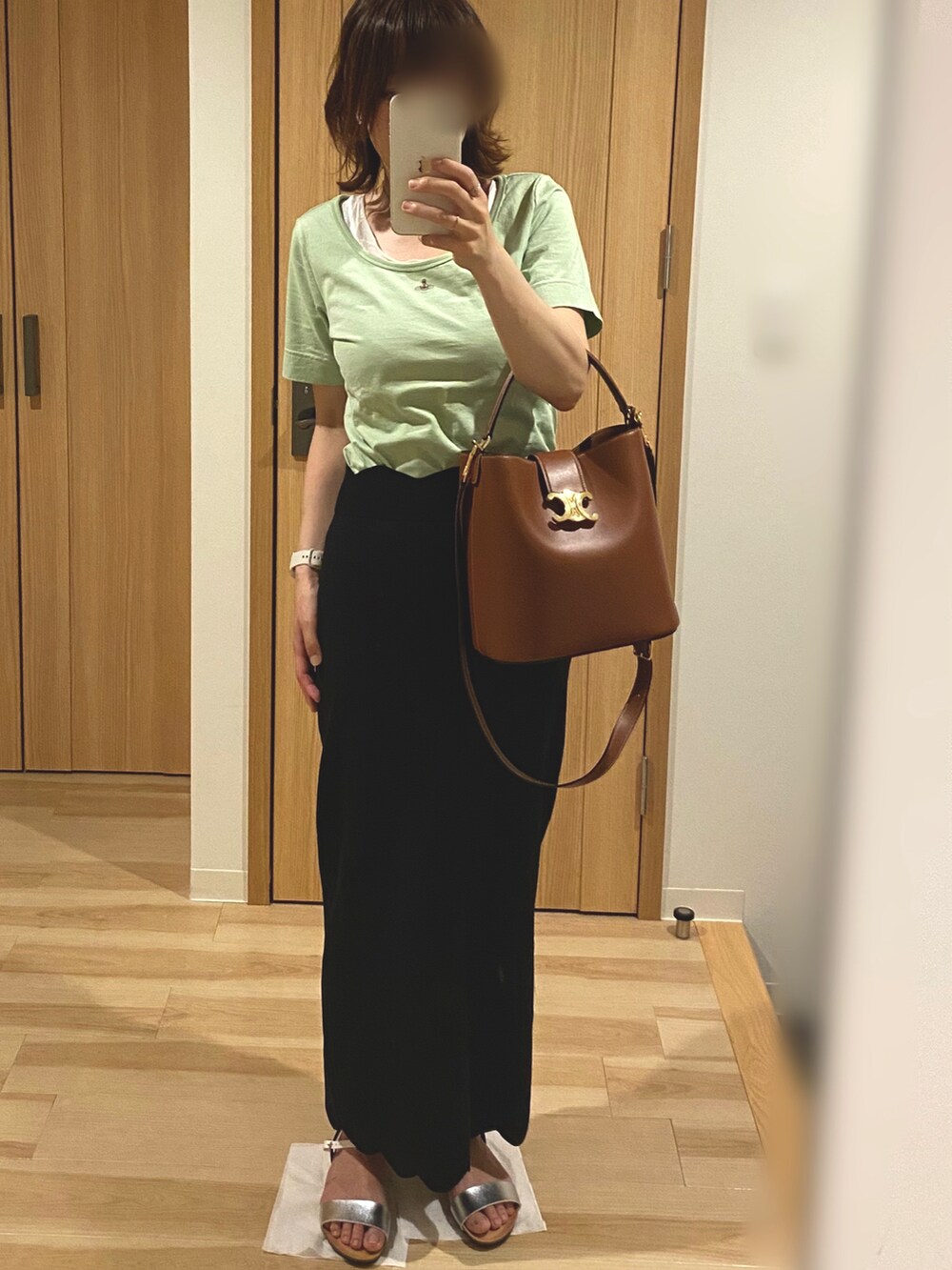 グリーン系のTシャツ/カットソー、ブラック系のスカート、シルバー系のサンダルを着用したレディースの夏コーディネートの2枚目の写真