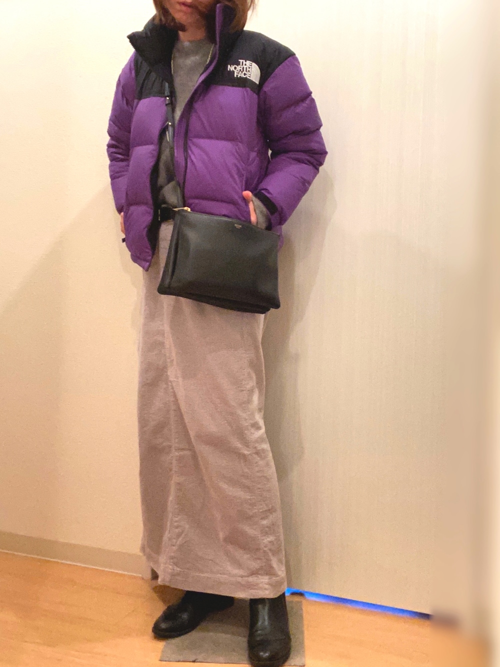 パープル系のダウンジャケット/コート、グレー系のニット/セーター、グレー系のスカートを着用したレディースの冬コーディネートの2枚目の写真