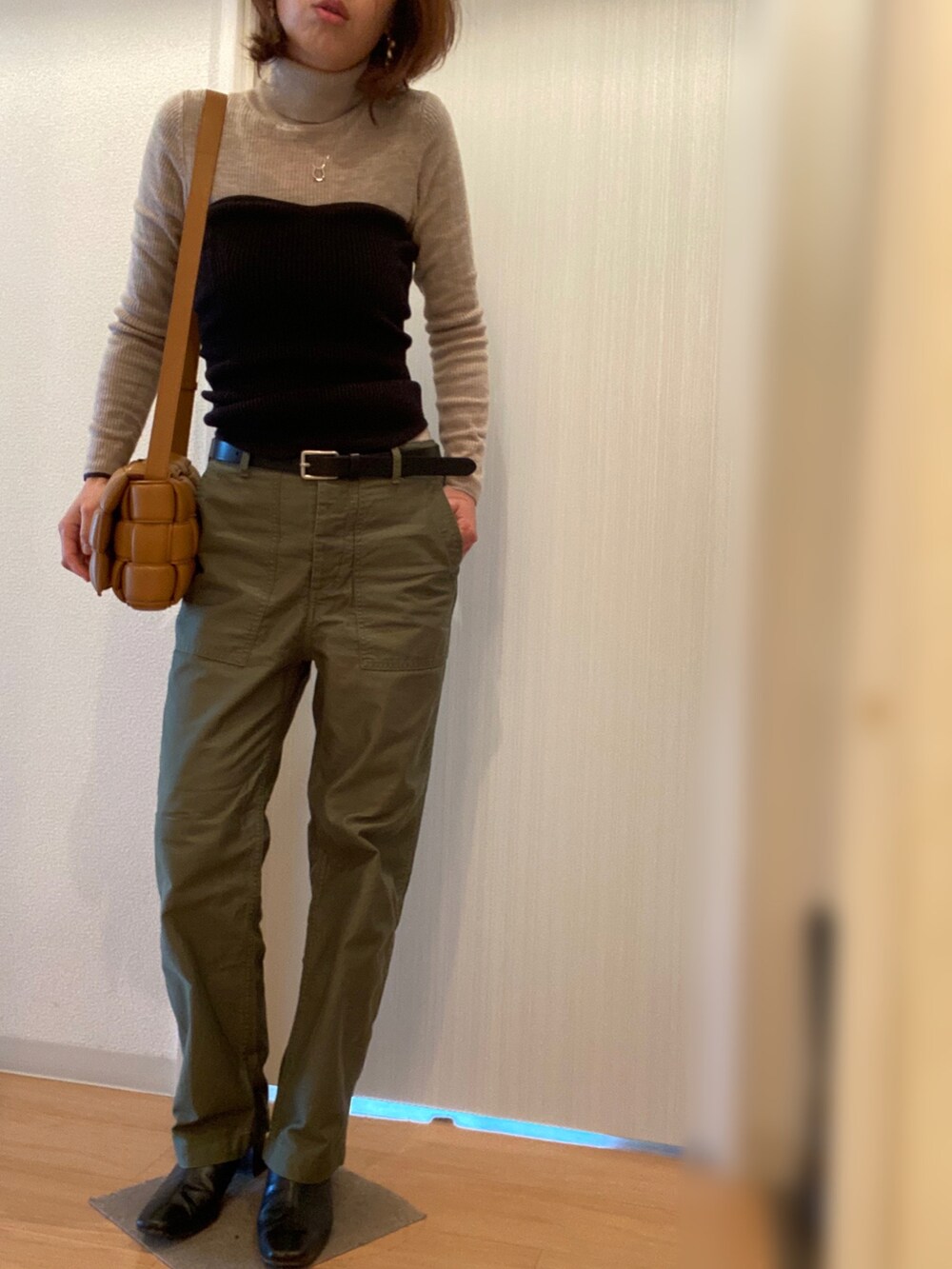 グリーン系のその他パンツ、ブラック系のブーツ、ブラック系のステンカラーコートを着用したレディースの冬コーディネートの2枚目の写真