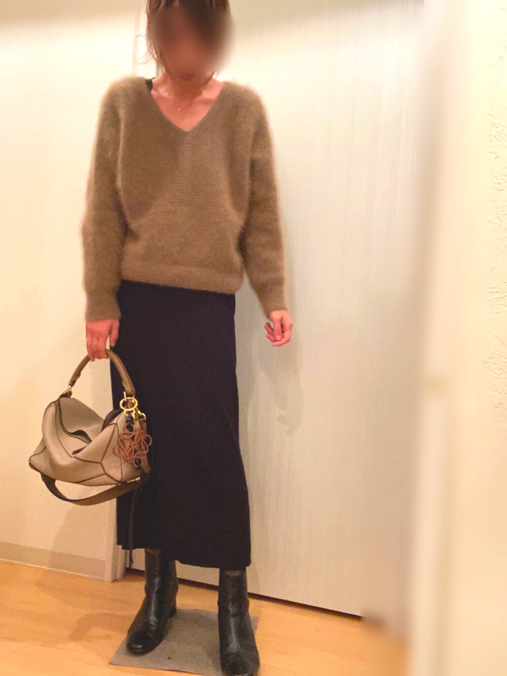 ブラウン系のニット/セーター、ブラック系のスカート、ブラック系のブーツを着用したレディースの冬コーディネートの2枚目の写真