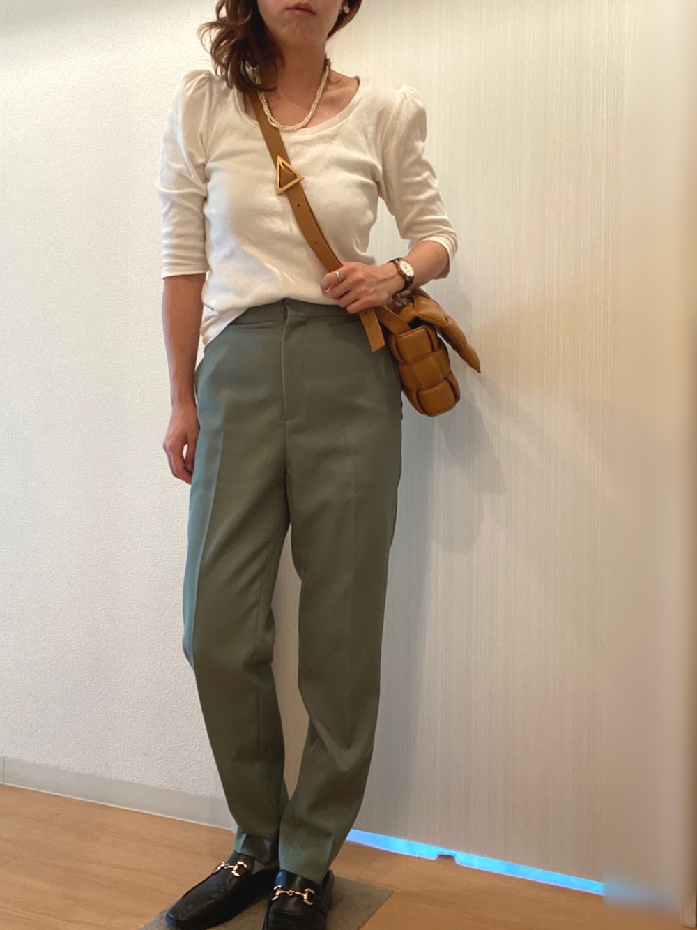 グリーン系のスラックス、ブラック系のローファー、ブルー系のアナログ腕時計を着用したレディースの秋コーディネートの2枚目の写真