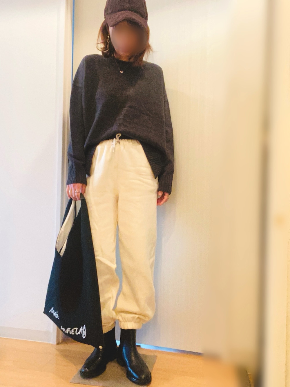 ブラック系のダウンジャケット/コート、グレー系のニット/セーター、ホワイト系のスウェットパンツを着用したレディースの冬コーディネートの2枚目の写真