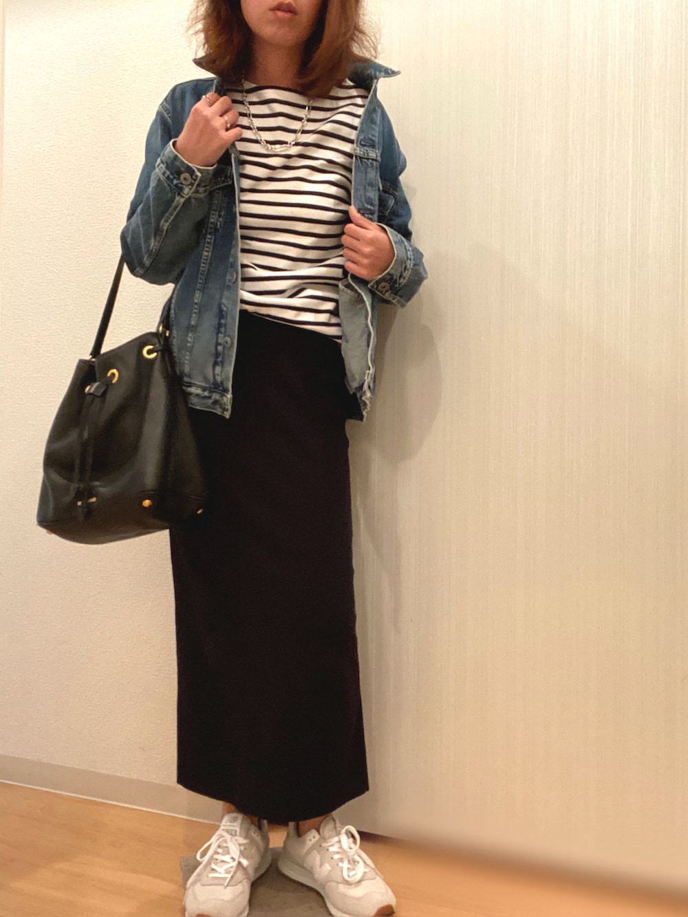 ブルー系のデニムジャケット、ホワイト系のTシャツ/カットソー、ブラック系のスカートを着用したレディースの秋コーディネートの2枚目の写真