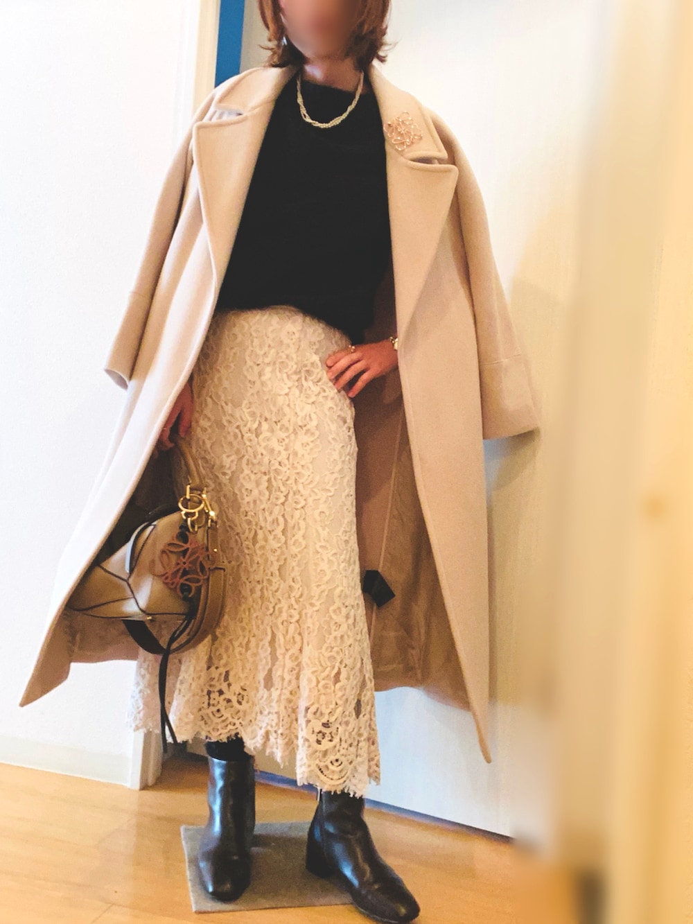 ブラック系のニット/セーター、ベージュ系のスカート、ブラウン系のブーツを着用したレディースの冬コーディネートの2枚目の写真