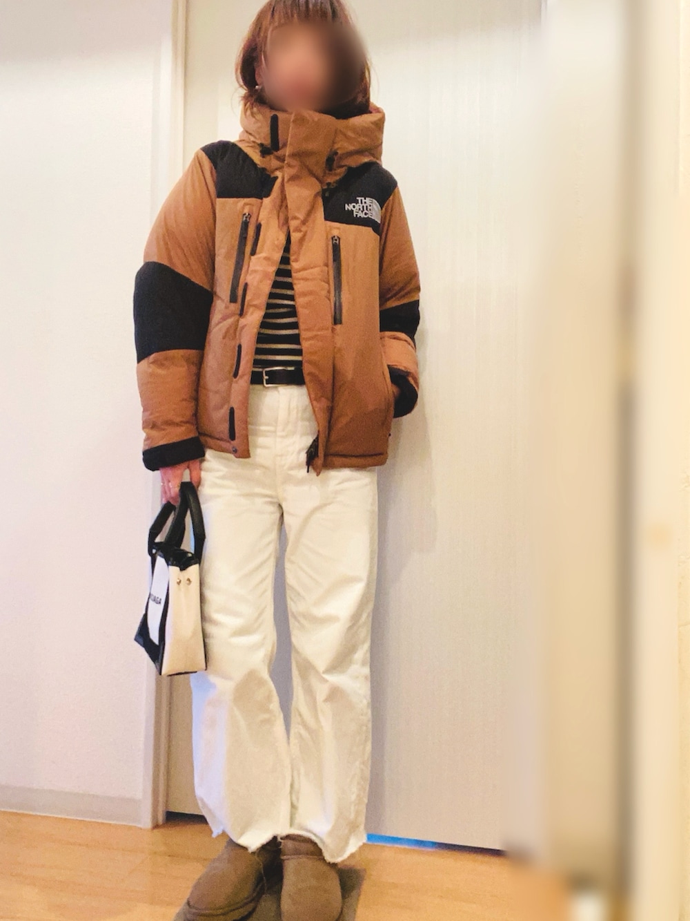 ベージュ系のダウンジャケット/コート、ブラック系のニット/セーター、ホワイト系のトートバッグを着用したレディースの冬コーディネートの2枚目の写真