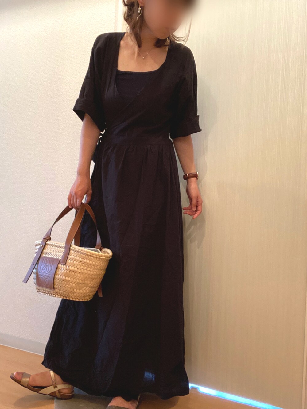 ブラック系のワンピース、ベージュ系のかごバッグ、ベージュ系のサンダルを着用したレディースの夏コーディネートの2枚目の写真