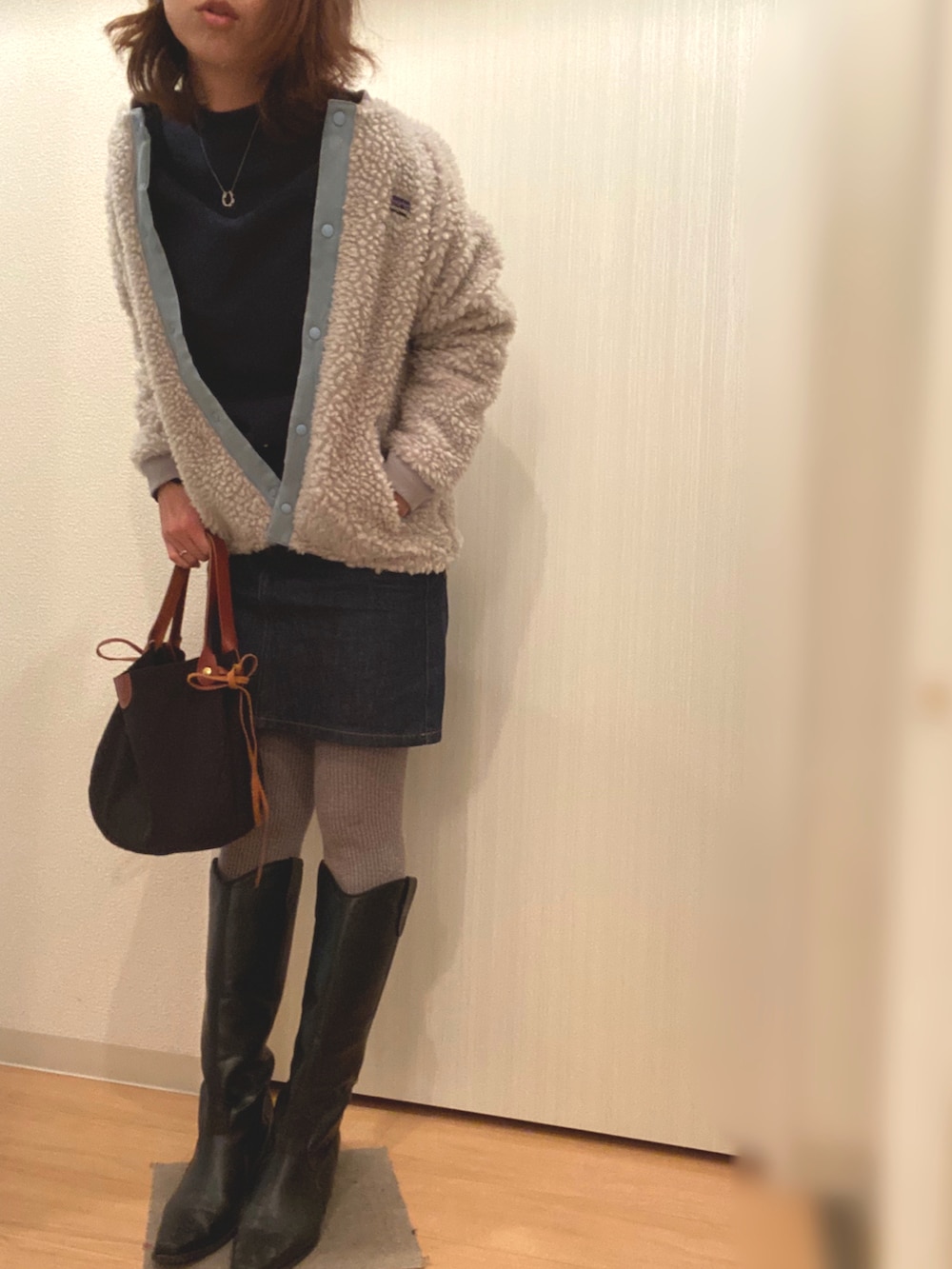 ブルー系のスウェット、ブルー系のデニムスカート、ホワイト系のその他アウターを着用したレディースの冬コーディネートの2枚目の写真