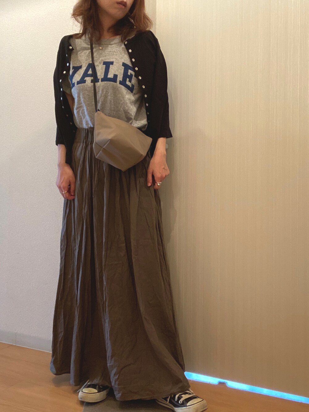 グレー系のTシャツ/カットソー、ブラウン系のスカート、ブラック系のカーディガン/ボレロを着用したレディースの秋コーディネートの2枚目の写真