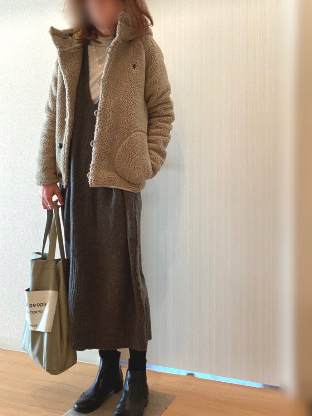 グレー系のワンピース、ブラック系のブーツ、グリーン系のトートバッグを着用したレディースの冬コーディネートの2枚目の写真