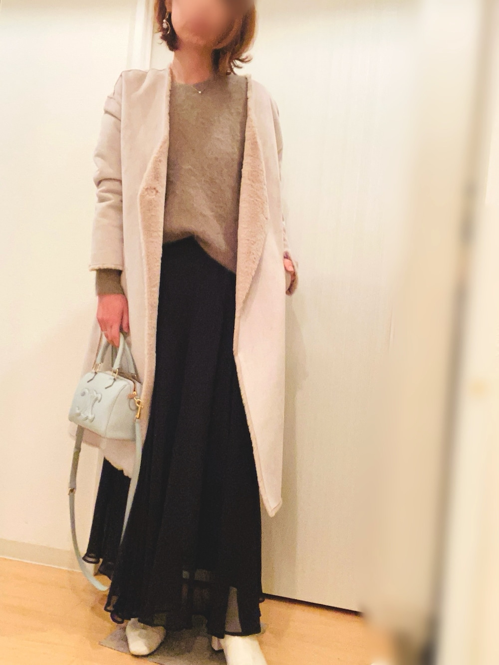 ブラウン系のニット/セーター、ブラック系のスカート、ホワイト系のブーツを着用したレディースの冬コーディネートの2枚目の写真