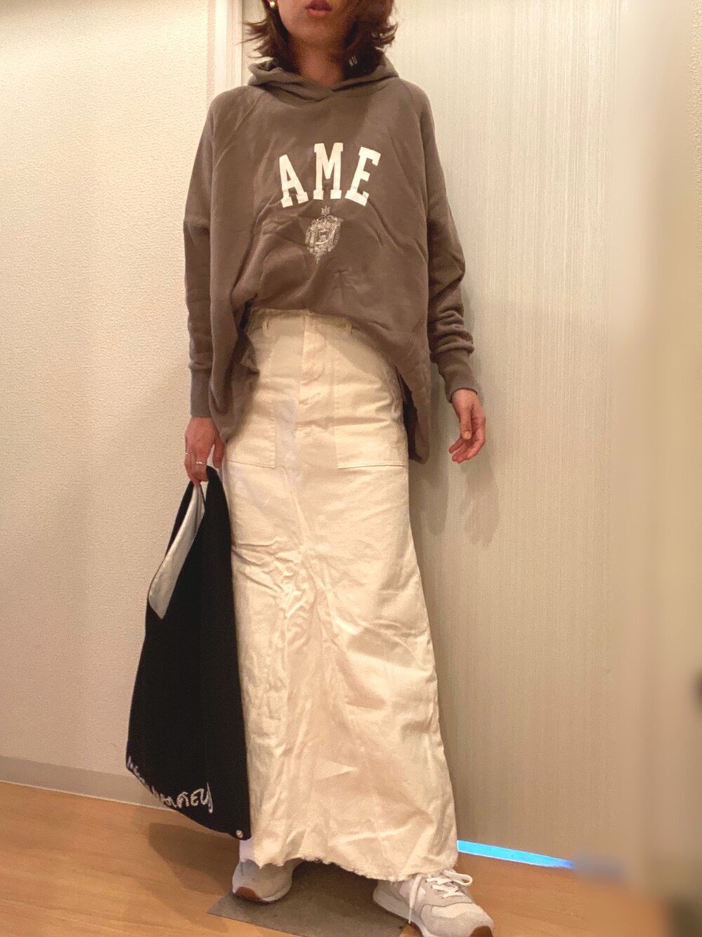 グリーン系のパーカー、ホワイト系のスカート、ブラック系のハンドバッグを着用したレディースの秋コーディネートの2枚目の写真